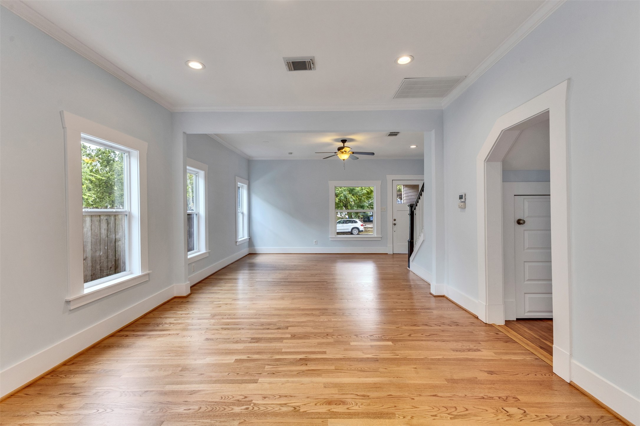Spacious and bright living area with beautiful hardwood floors, ample natural light from multiple windows, and elegant crown molding. Perfect for entertaining or relaxing.