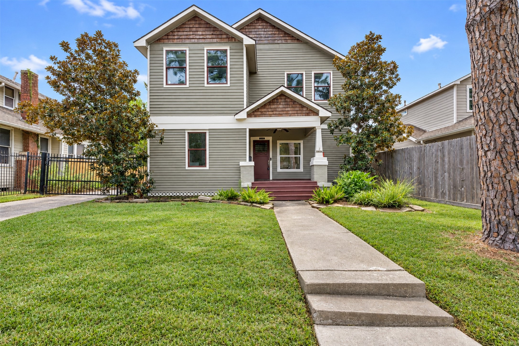 Charming two-story home with a welcoming covered front porch, surrounded by lush greenery and manicured lawns. A perfect blend of classic design and modern comforts.