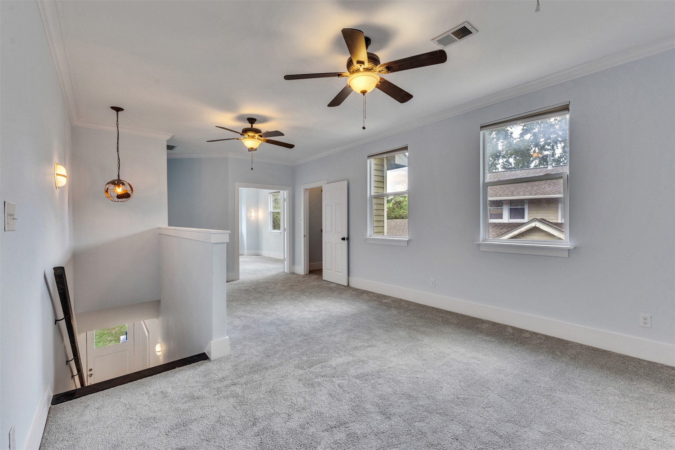 Spacious upper-level landing with plush carpeting, abundant natural light, and ceiling fans for comfort.