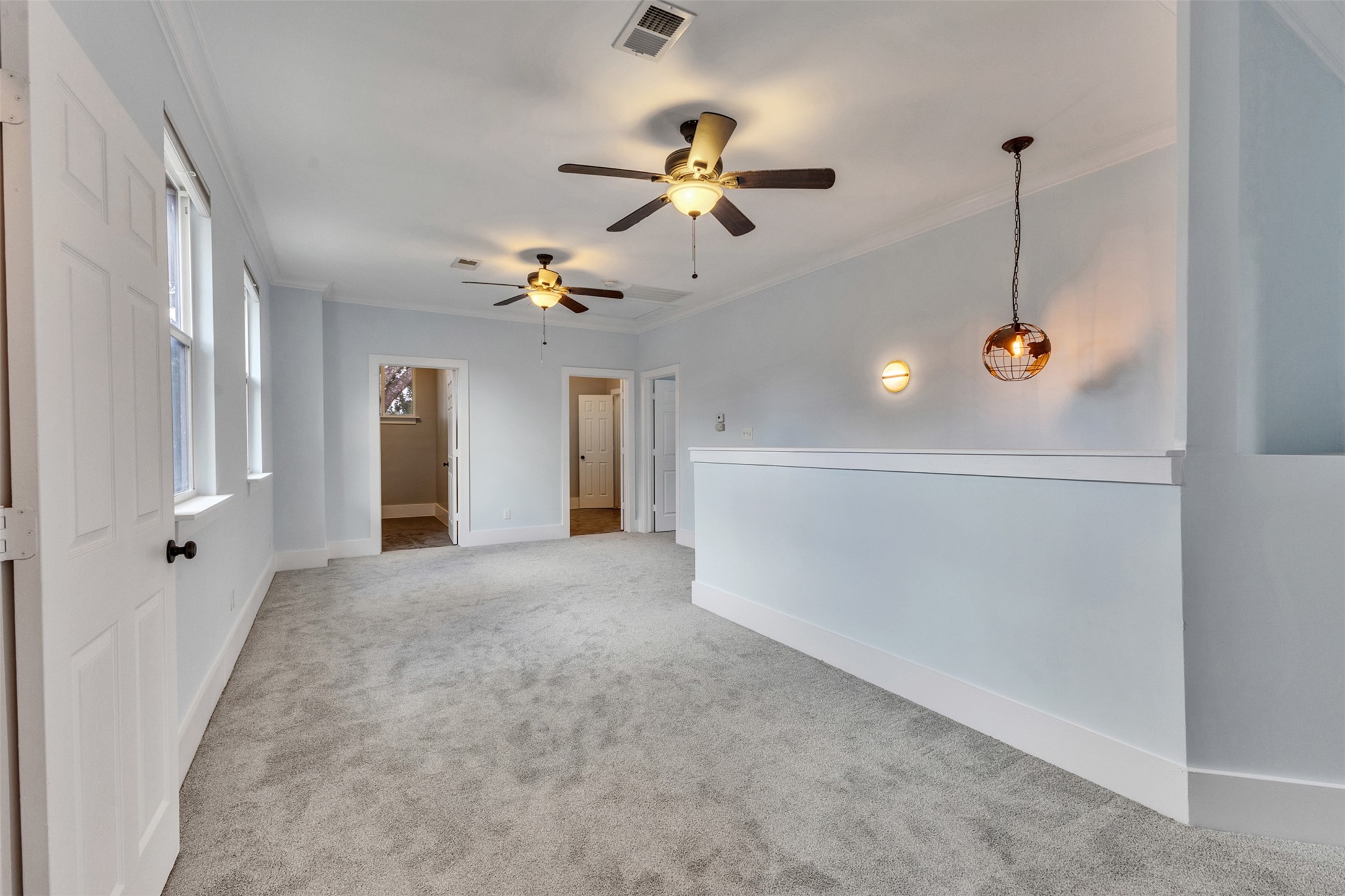 Spacious hallway with plush carpeting, modern ceiling fans, and stylish lighting, leading to multiple rooms for versatile use.