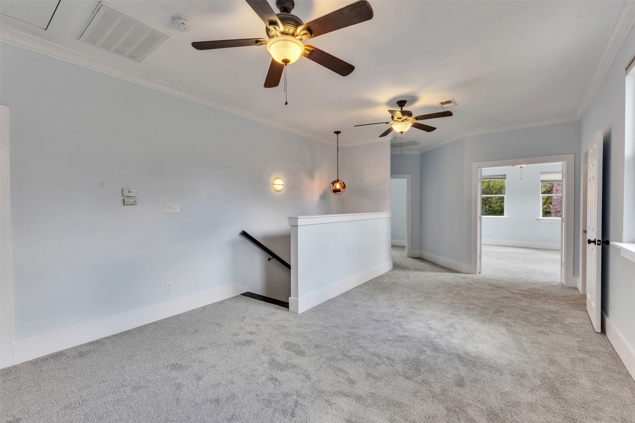Spacious and airy landing area with plush carpeting, modern ceiling fans, and ample natural light, leading to additional rooms.