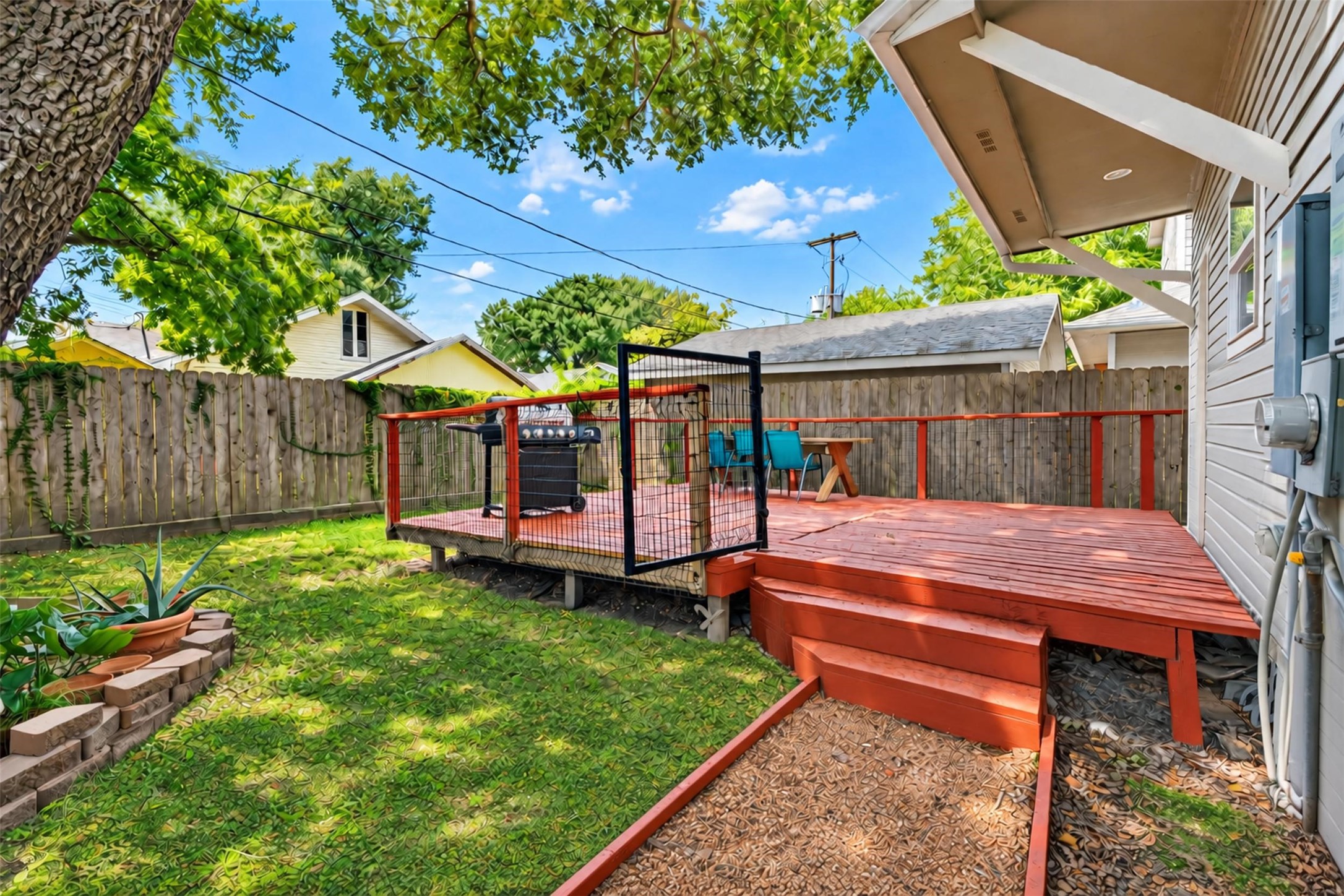 Charming backyard featuring a spacious wooden deck perfect for outdoor dining and entertaining, surrounded by lush greenery and mature trees for added privacy.
