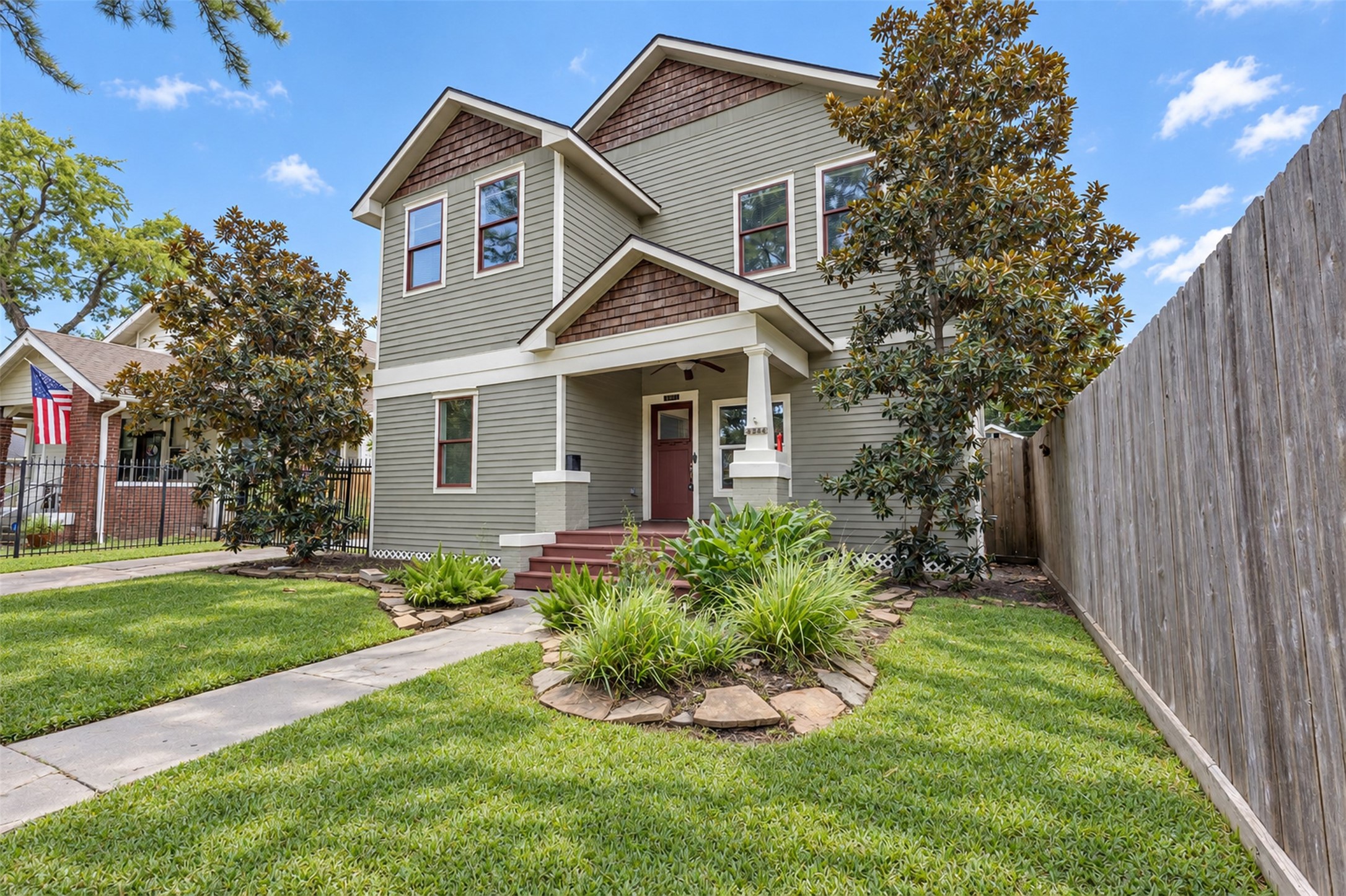 Charming two-story home with classic craftsman architecture, featuring a welcoming front porch, manicured lawn, and mature trees for added curb appeal.