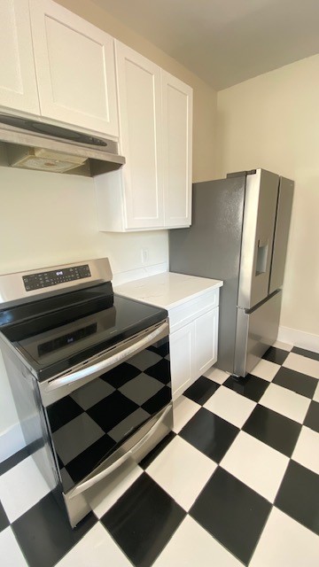 Modern kitchen with sleek stainless steel appliances, crisp white cabinetry, and a classic black-and-white checkered floor.