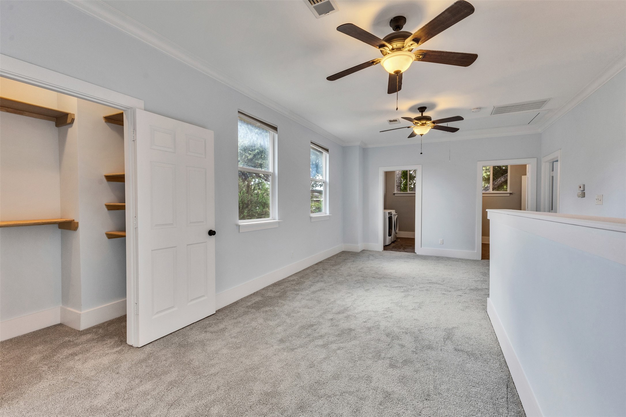 Spacious, light-filled room with plush carpeting, featuring two ceiling fans and a convenient walk-in closet.