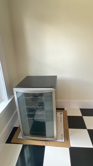 Charming corner with a modern wine cooler, set against stylish black and white checkered flooring, perfect for entertaining.