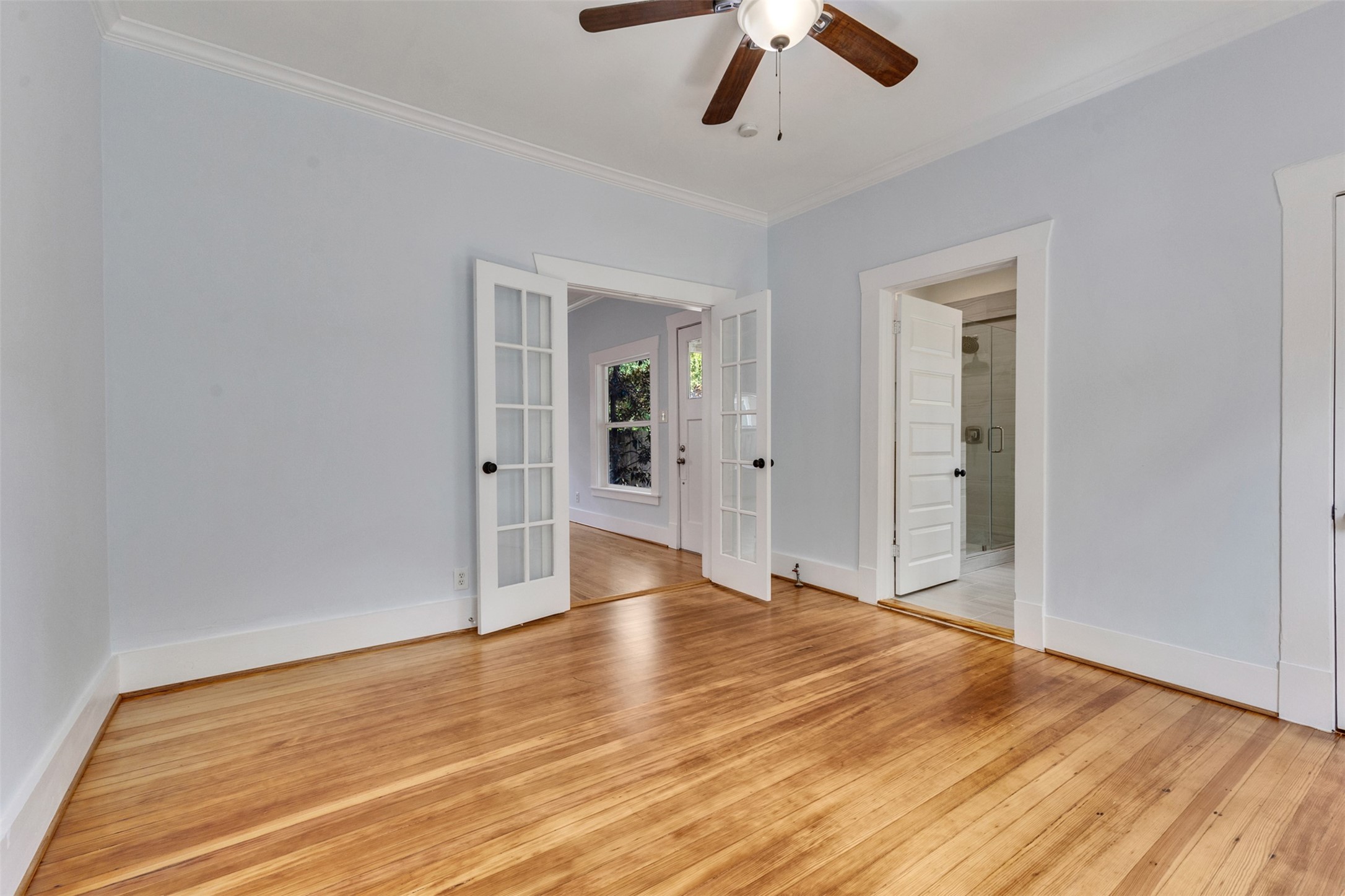 Spacious room with beautiful hardwood floors, elegant French doors, and abundant natural light, offering a warm and inviting atmosphere.