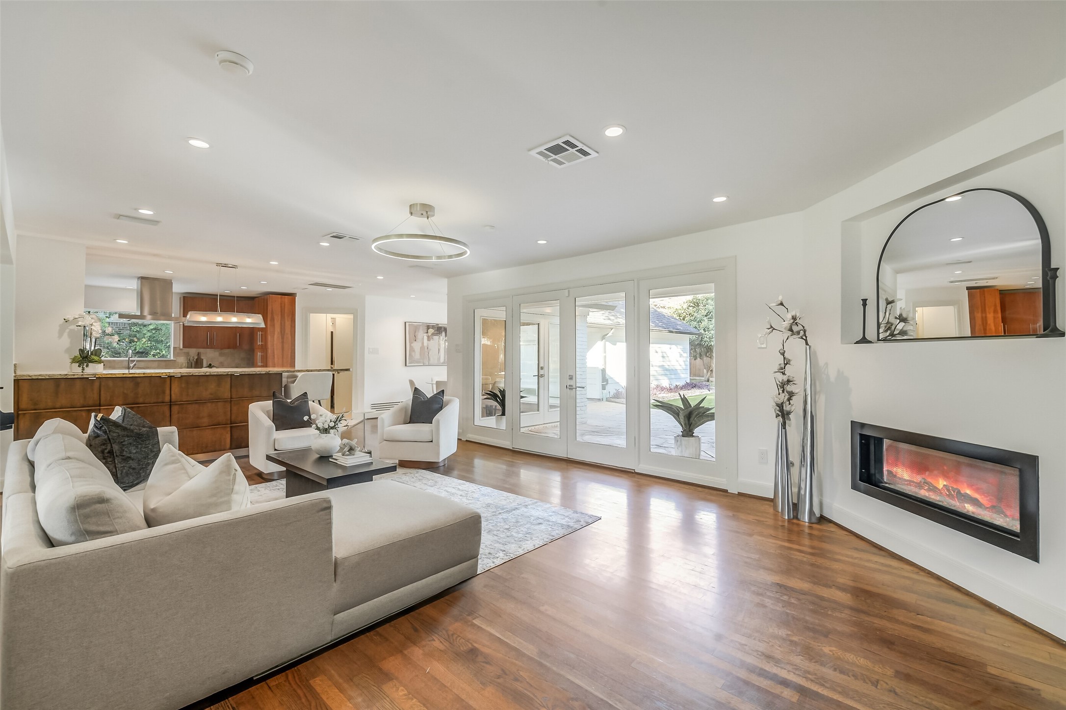 Open-concept living room with a seamless flow into the kitchen and French doors that open to the beautiful backyard.