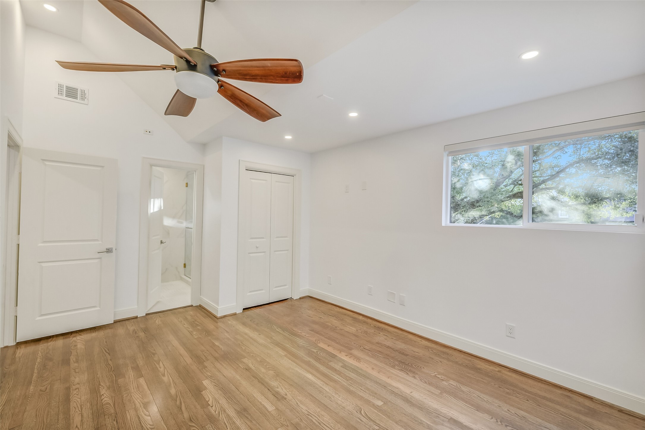 Another charming second-floor secondary bedroom offering bathroom en-suite, beautiful hardwood floors, recessed lighting, and expansive windows that invite abundant natural light, creating a bright and comfortable retreat.