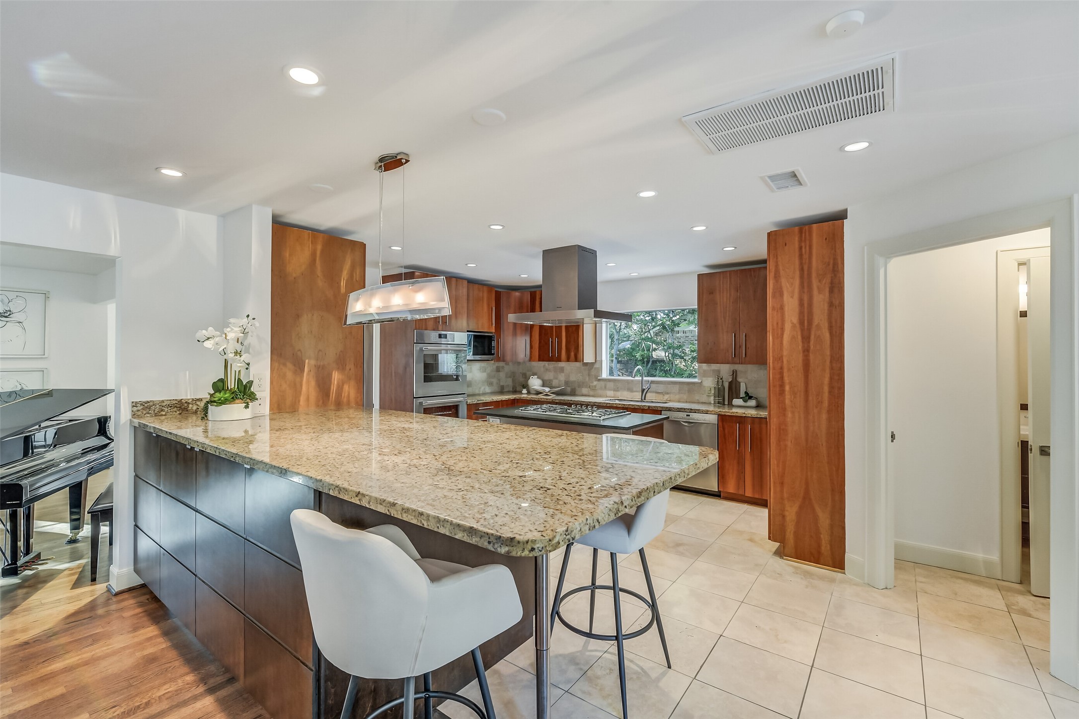 Spacious and inviting kitchen showcasing rich wood cabinetry, granite countertops, stainless steel appliances, and an expansive breakfast bar offering ample seating for casual dining and entertaining.