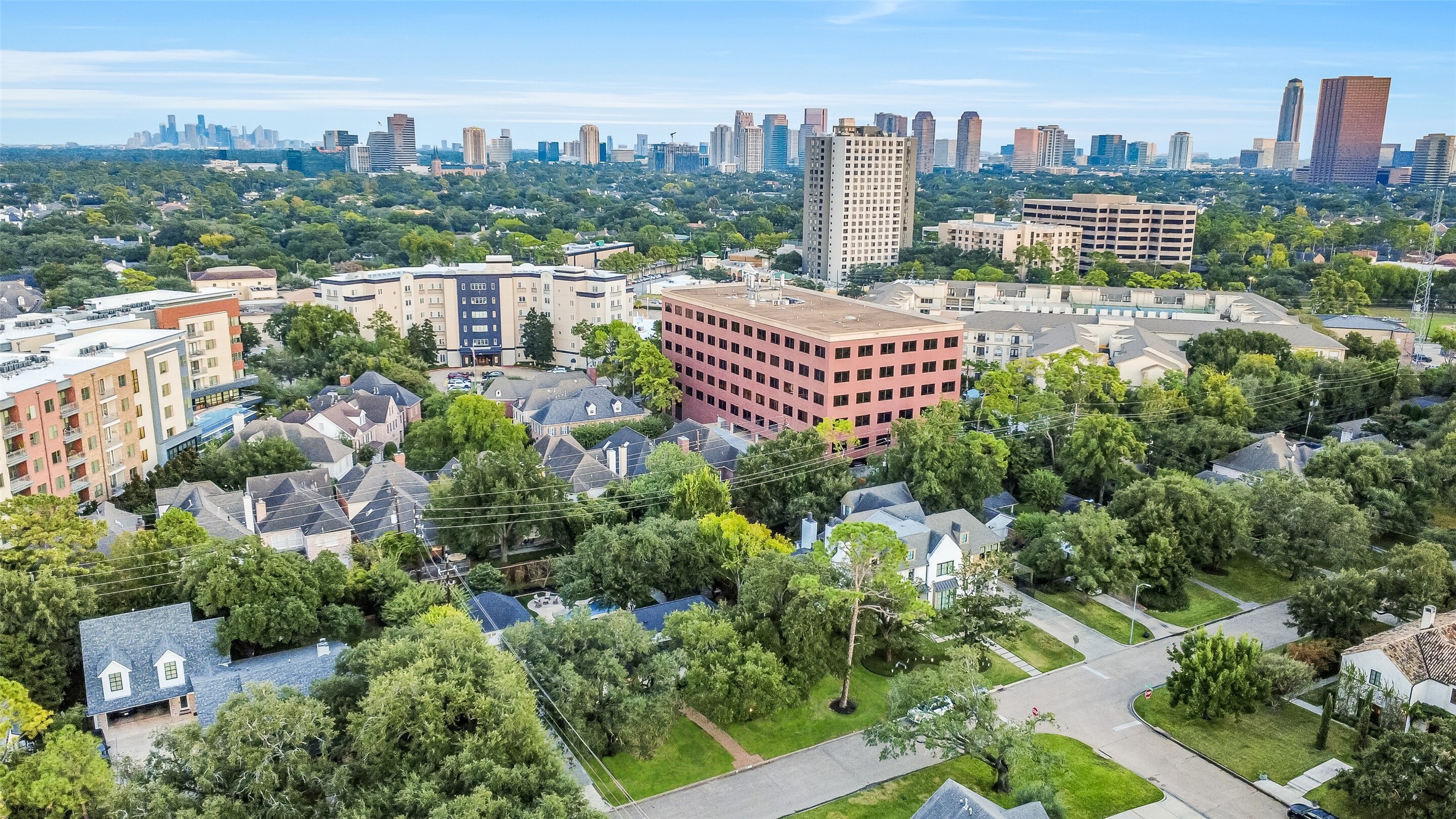Aerial perspective showcasing the home's established, tree-lined neighborhood with Houston's impressive skyline in the distance.