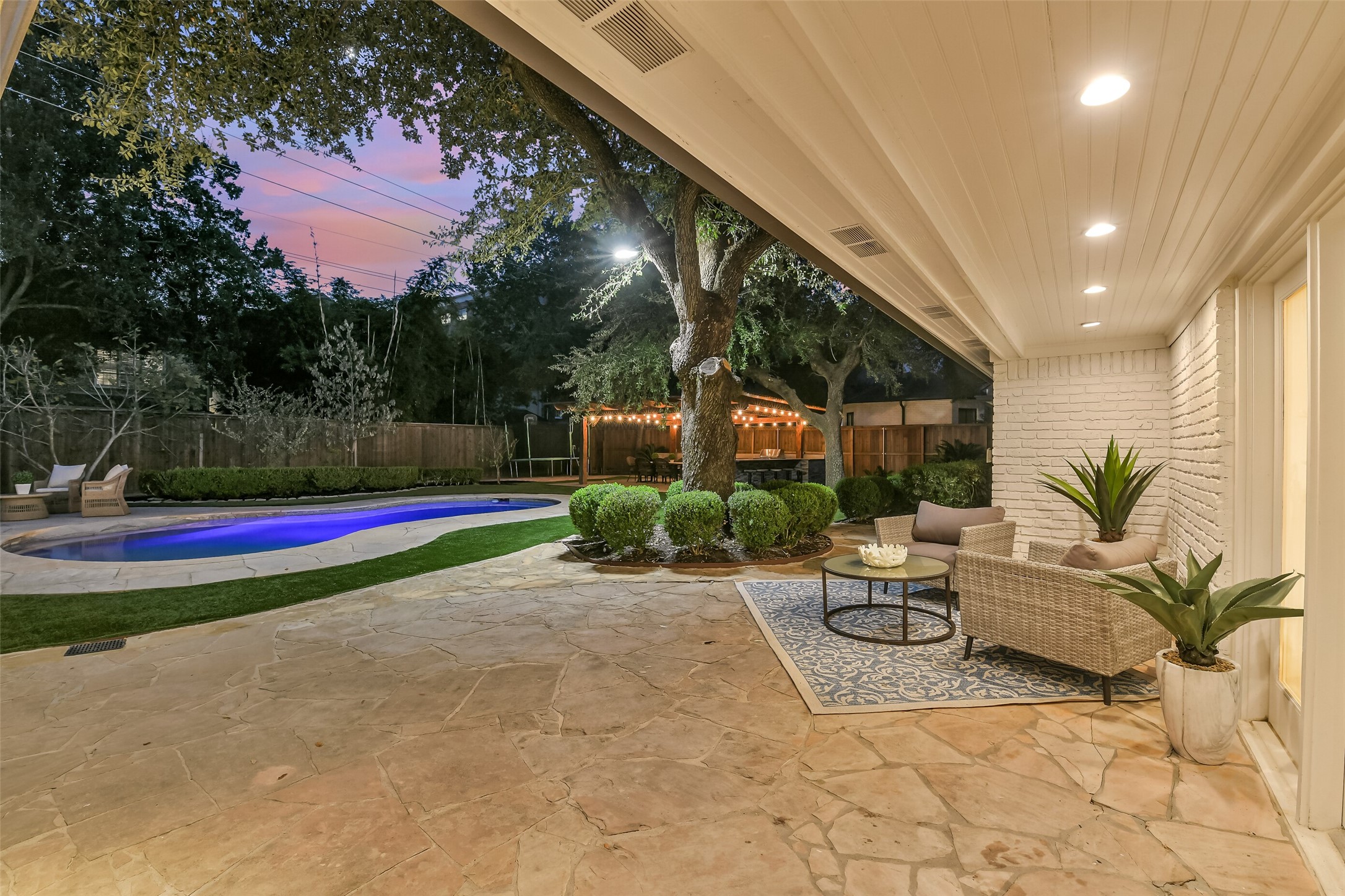Relax and unwind on this charming covered patio, featuring beautiful stone flooring, recessed lighting, and inviting seating areas. Overlooking the sparkling pool and lushly landscaped backyard, this peaceful retreat is perfect for morning coffee, quiet evenings, or gathering with family and friends.