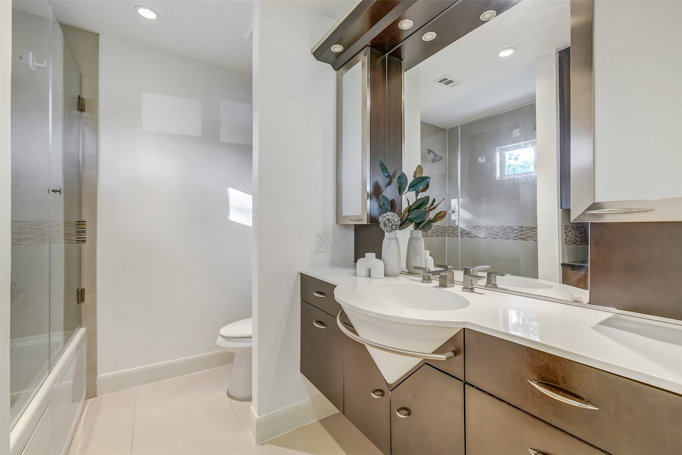 Beautifully appointed secondary en-suite bathroom featuring contemporary finishes, a stylish vanity with generous counter space and storage, and a tub/shower combination with decorative tile accents.