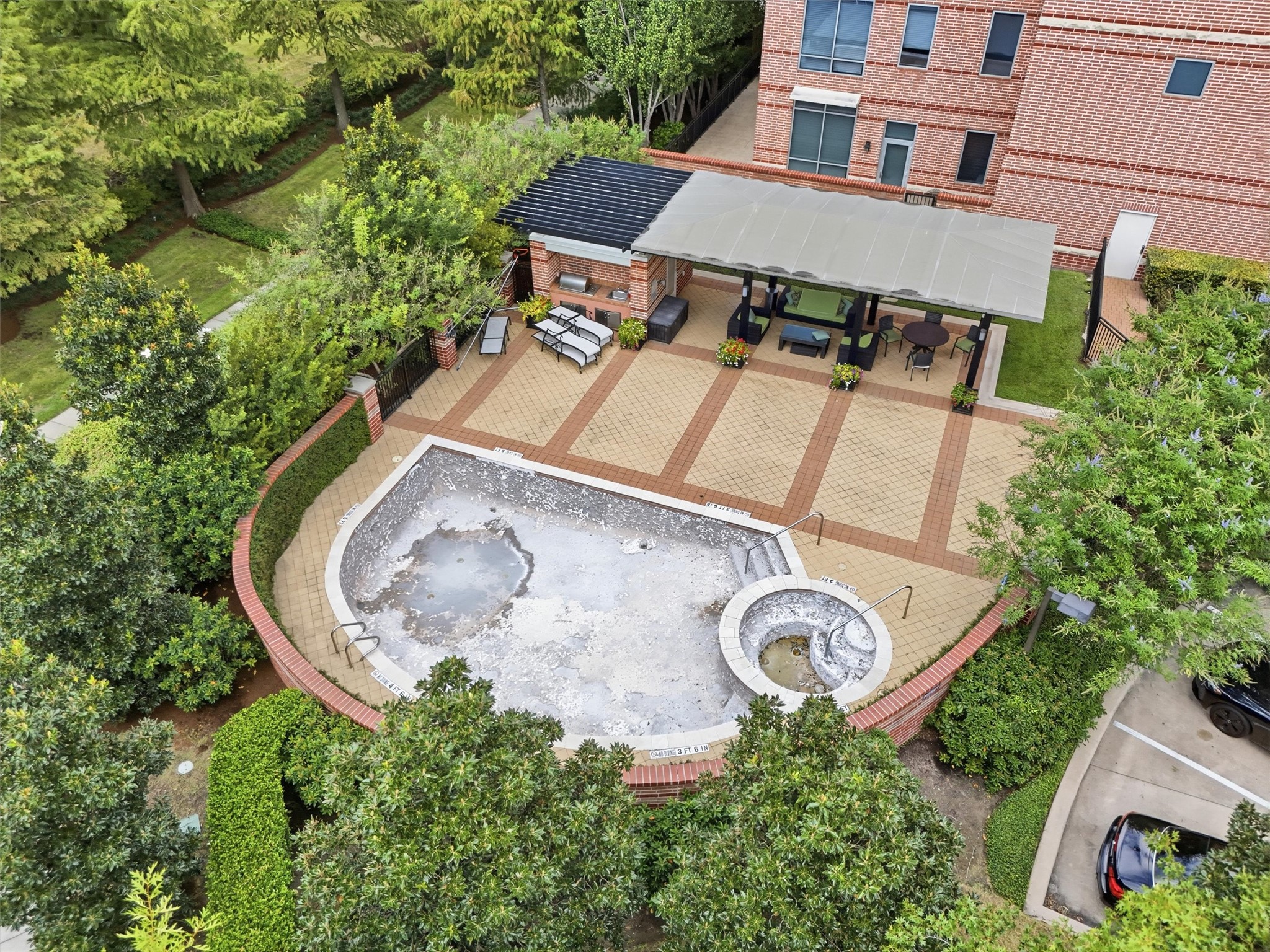 A bird's-eye view of the community pool and outdoor gathering areas surrounded by lush greenery. Currently being replastured.
