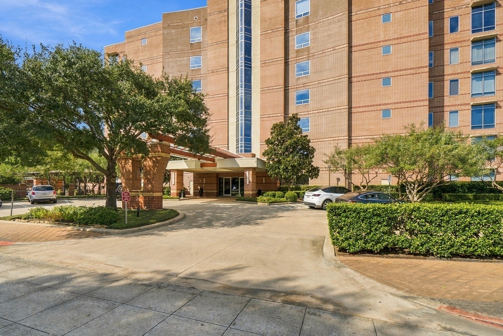 Beautiful condominium exterior surrounded by mature trees, manicured landscaping, and welcoming grounds.