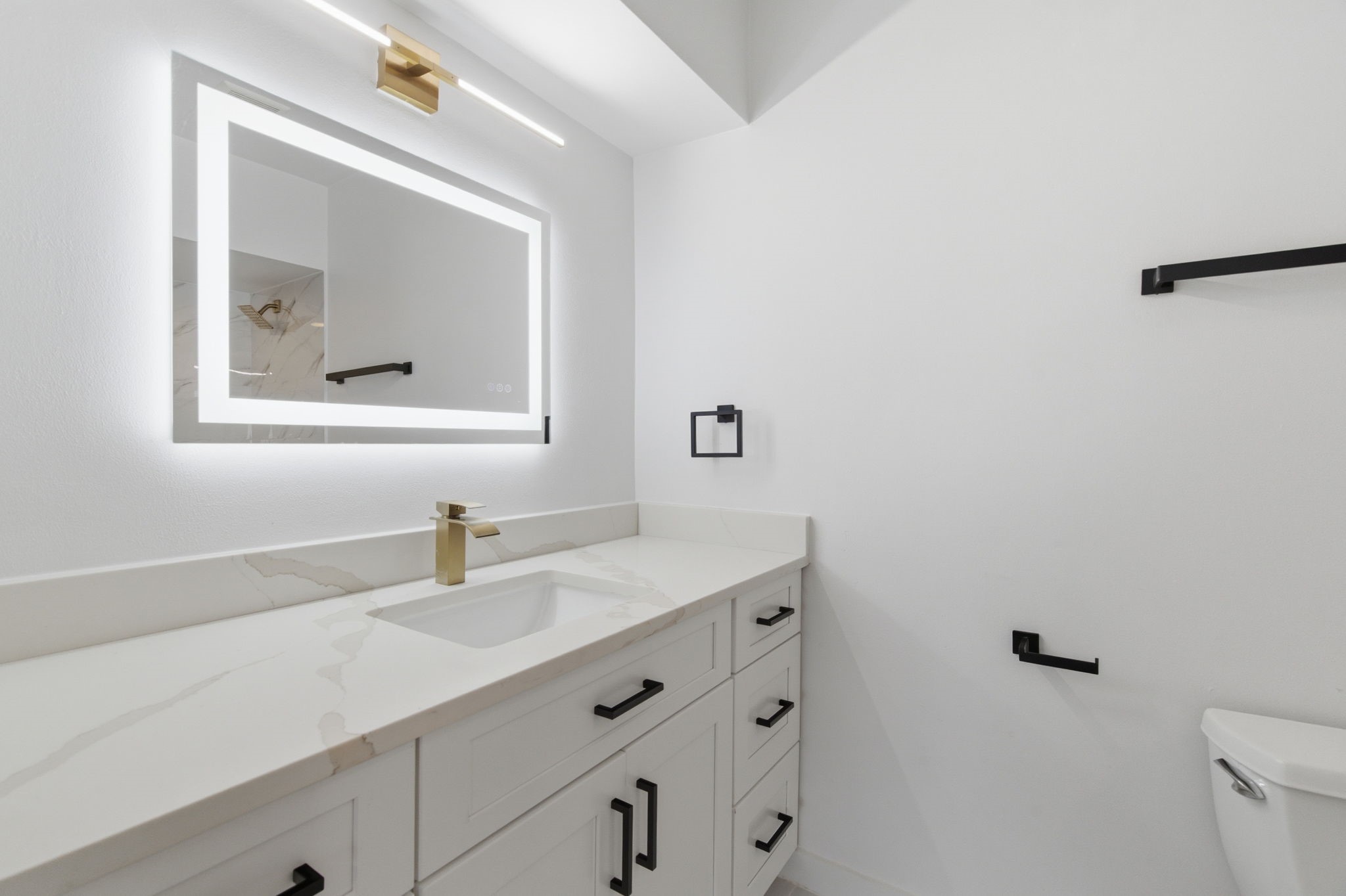 Clean lines, mixed metal finishes, and an illuminated mirror give the primary bathroom a polished, modern look.