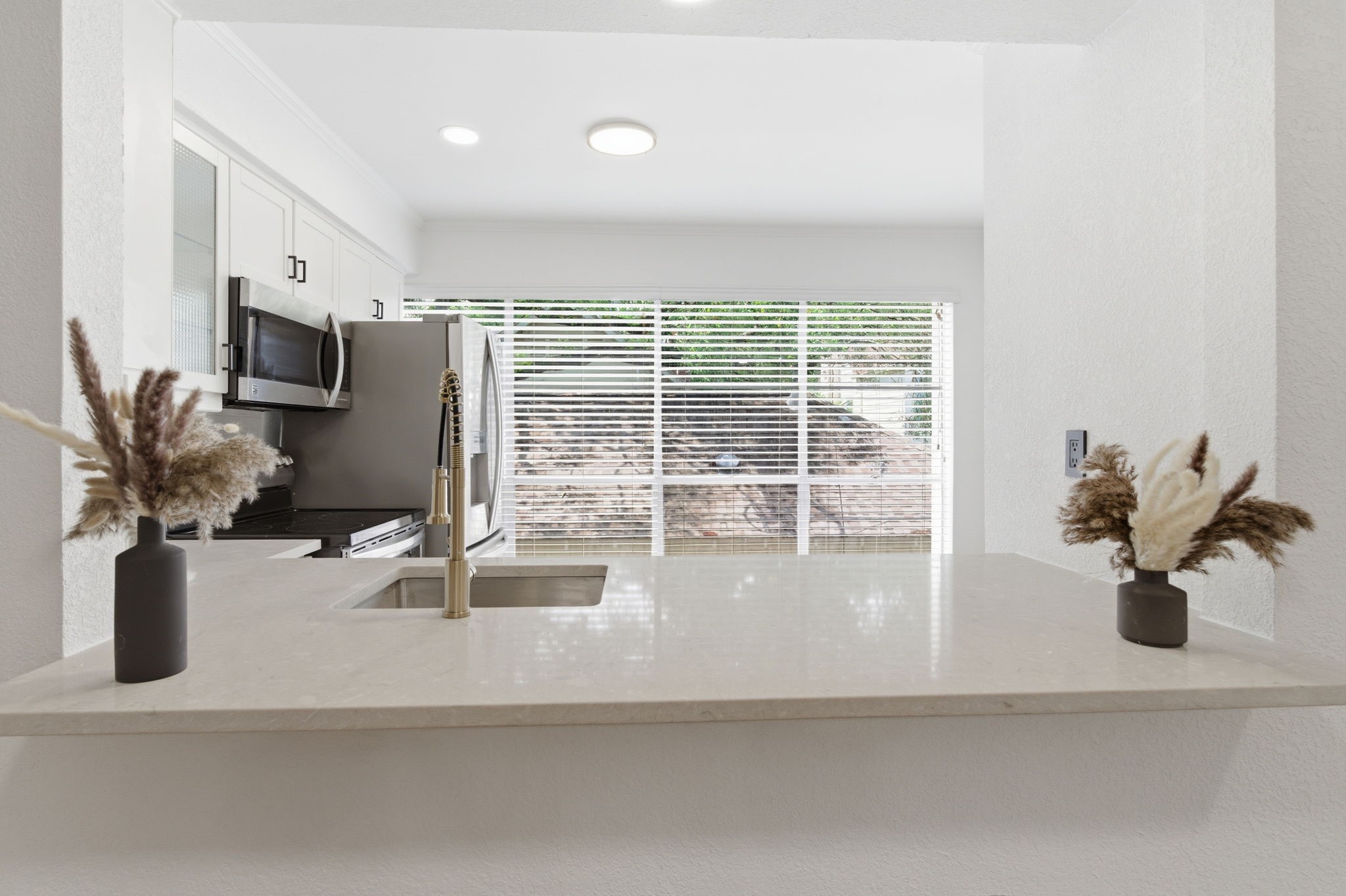 The kitchen pass through keeps the conversation flowing and provides additional space for serving, seating, or casual meals.