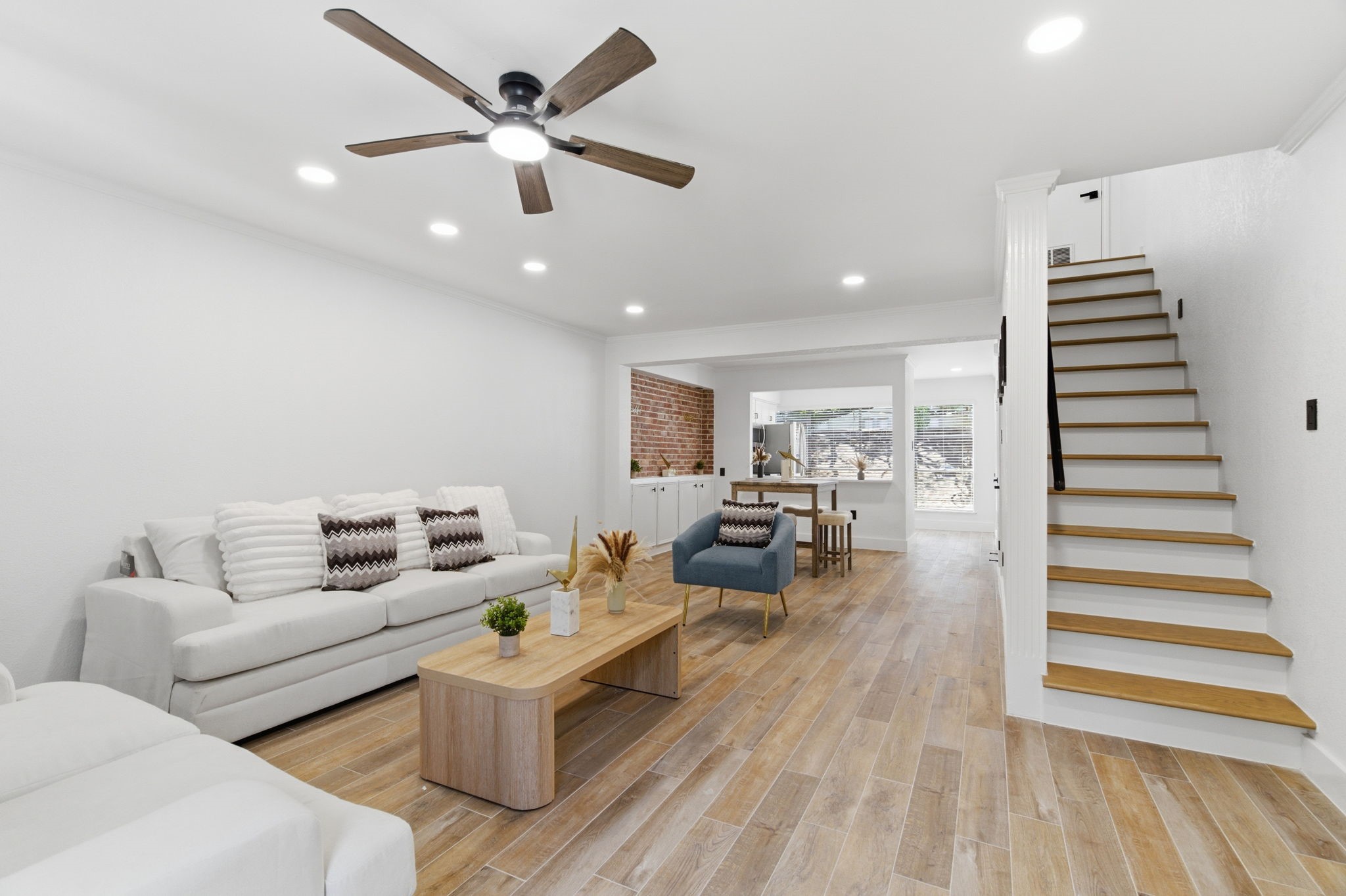 The open living room sets the tone with warm wood look tile, recessed lighting, and a clear view through the dining area and kitchen. The open living room sets the tone with warm wood look tile, recessed lighting, and a clear view through the dining area and kitchen.