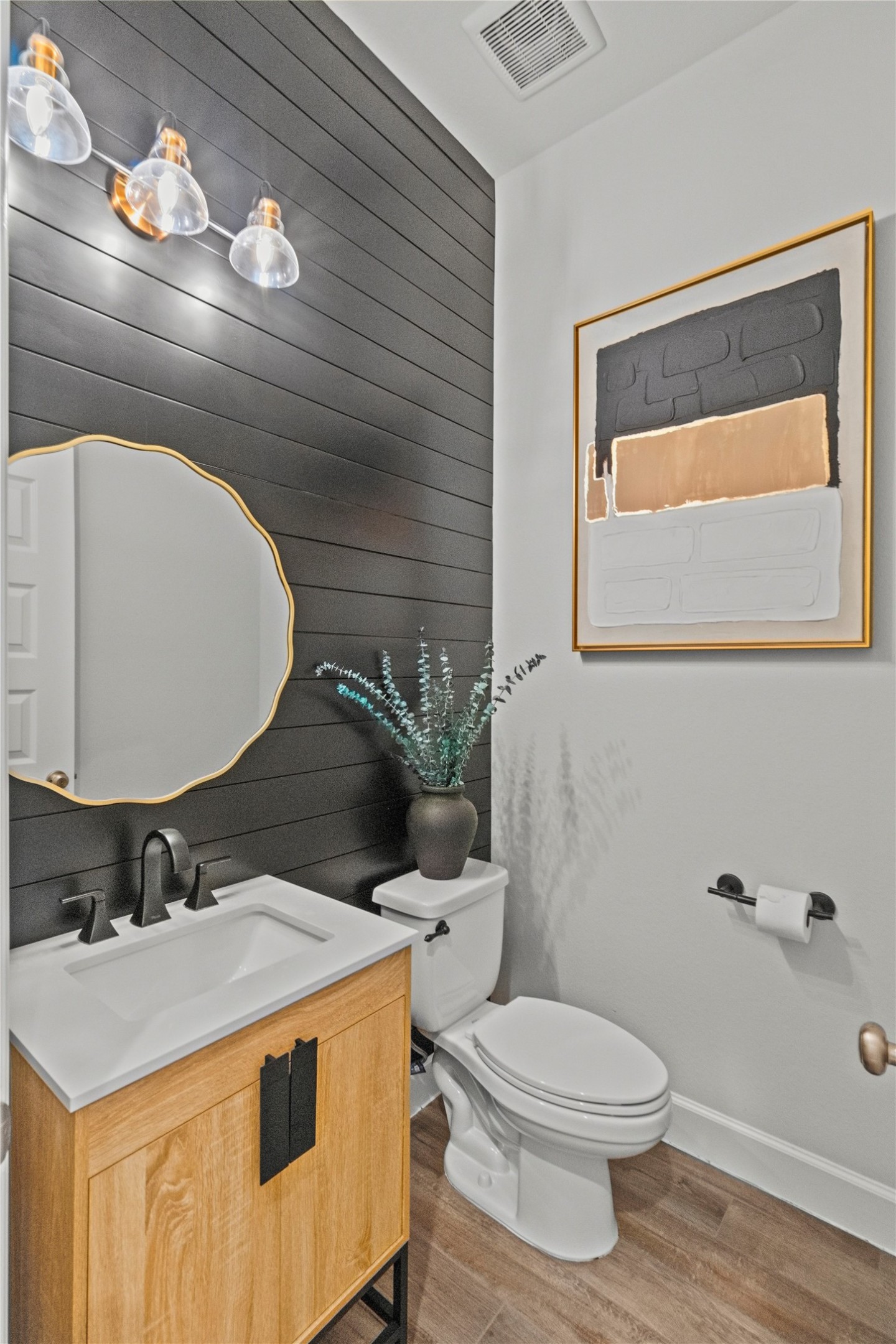 Chic powder room with a modern black shiplap accent wall, sleek fixtures, and stylish artwork, offering a blend of contemporary and rustic charm.