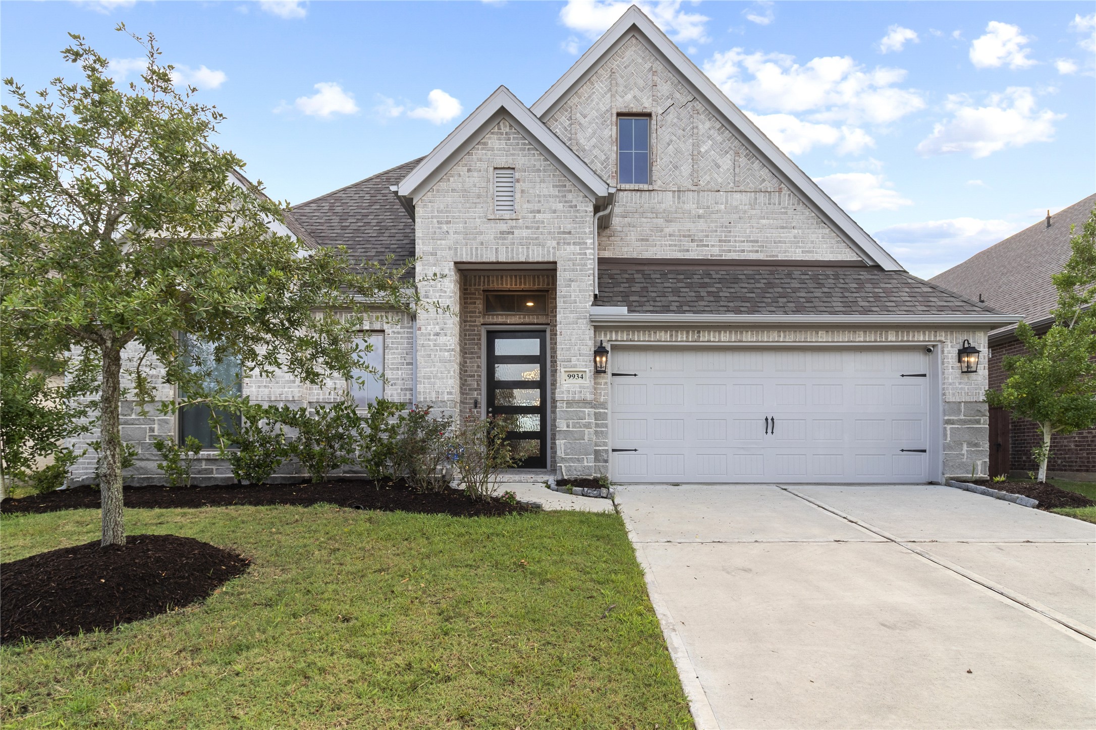 Charming single-story home with a modern brick exterior, featuring a welcoming front porch and a spacious two-car garage.