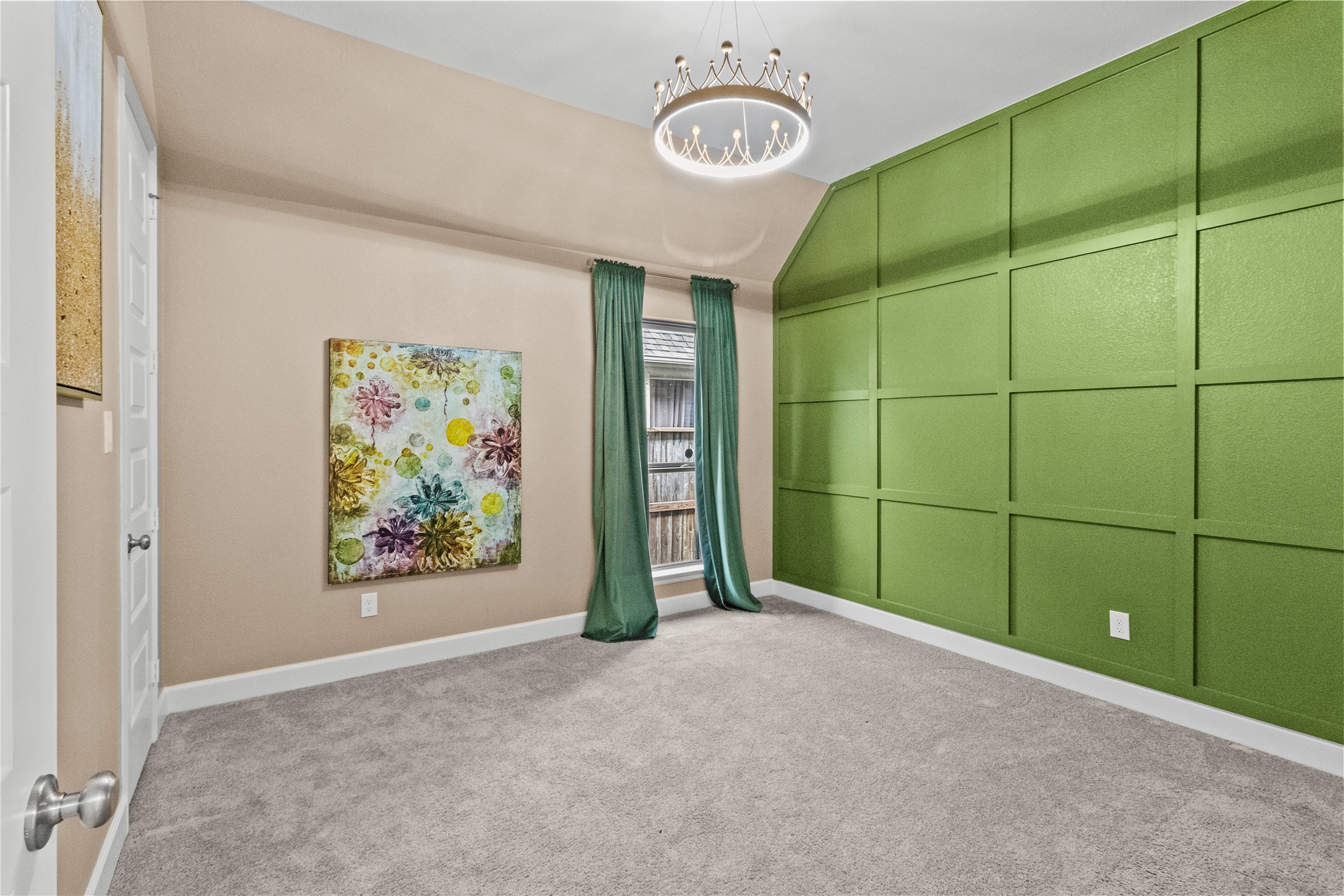 A bright room featuring a striking green accent wall, plush carpet, and a stylish chandelier, perfect for a cozy and inviting space.