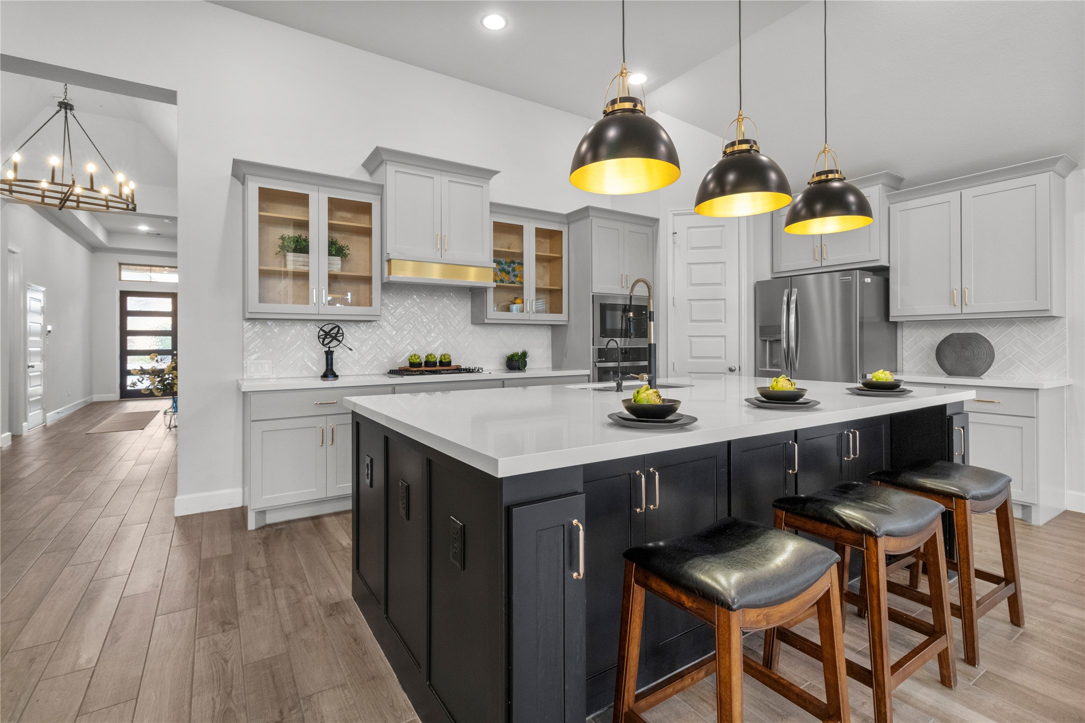 Stunning modern kitchen featuring a spacious island with sleek black cabinetry, elegant pendant lighting, and stainless steel appliances.