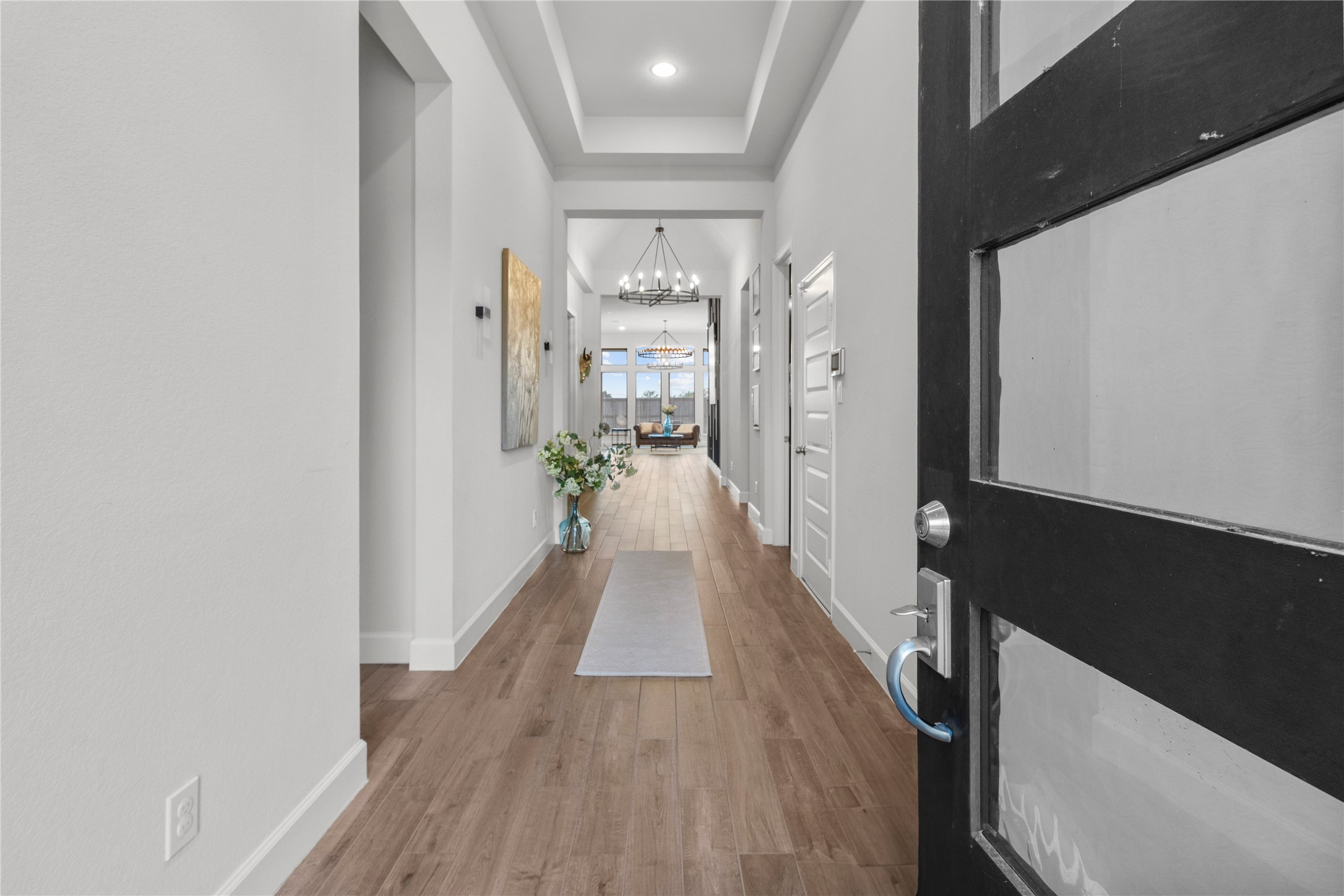 Step into a welcoming foyer with elegant hardwood flooring and a modern chandelier, leading to a bright, open living space.