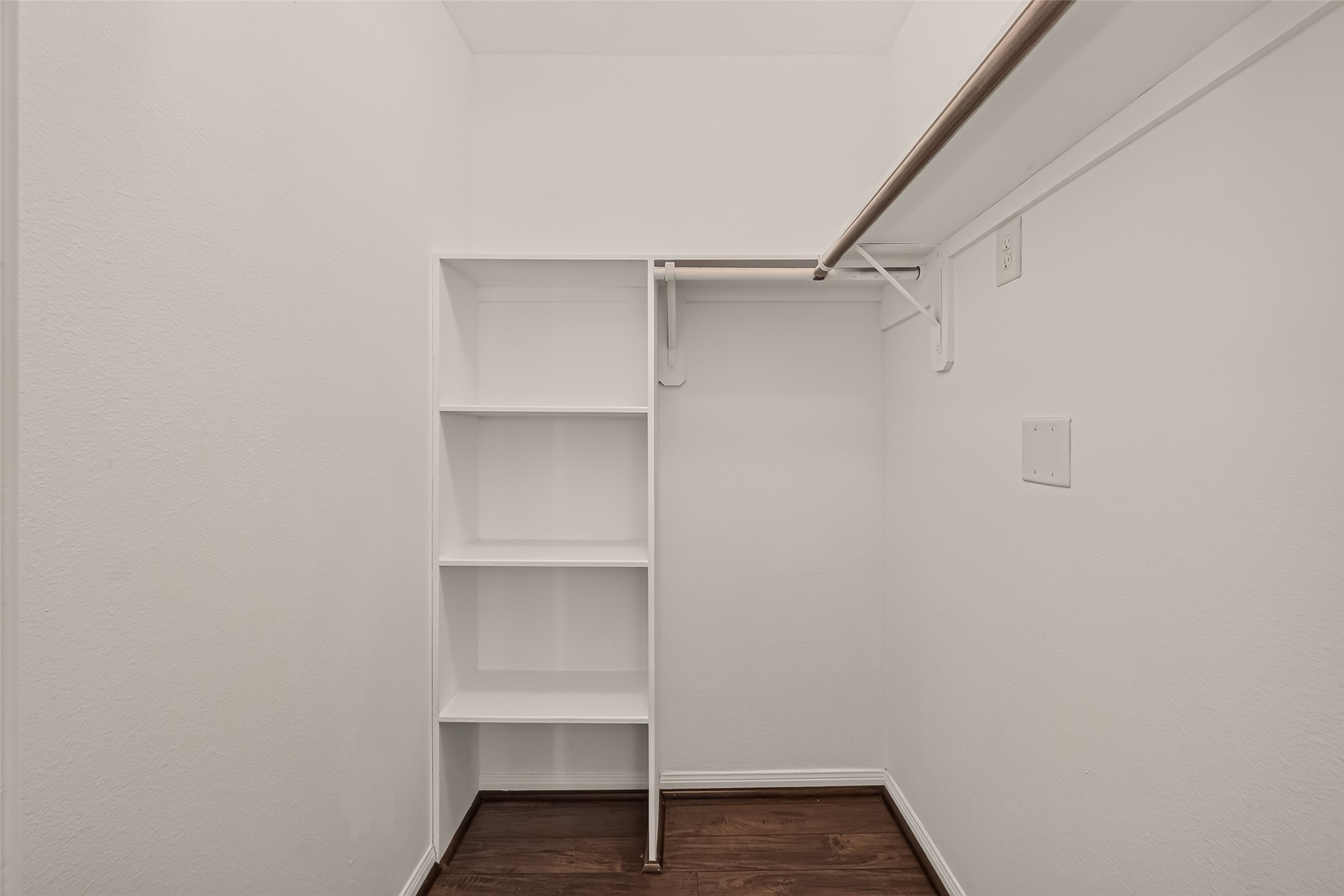Spacious walk-in closet featuring built-in shelving and ample hanging space, complemented by a clean, modern design.