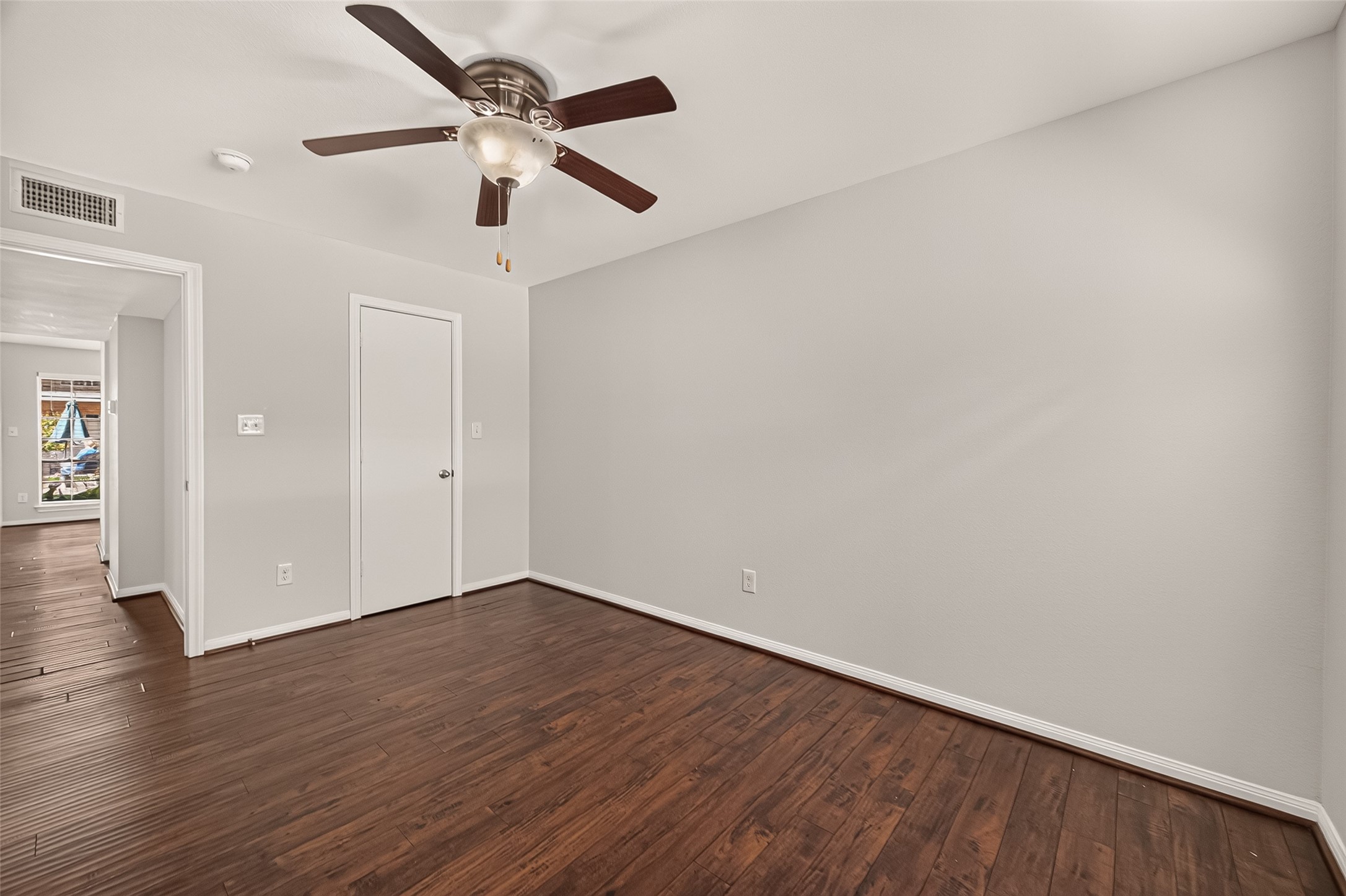Inviting room with sleek hardwood flooring, neutral walls, and a ceiling fan, offering a versatile space suitable for any design style.