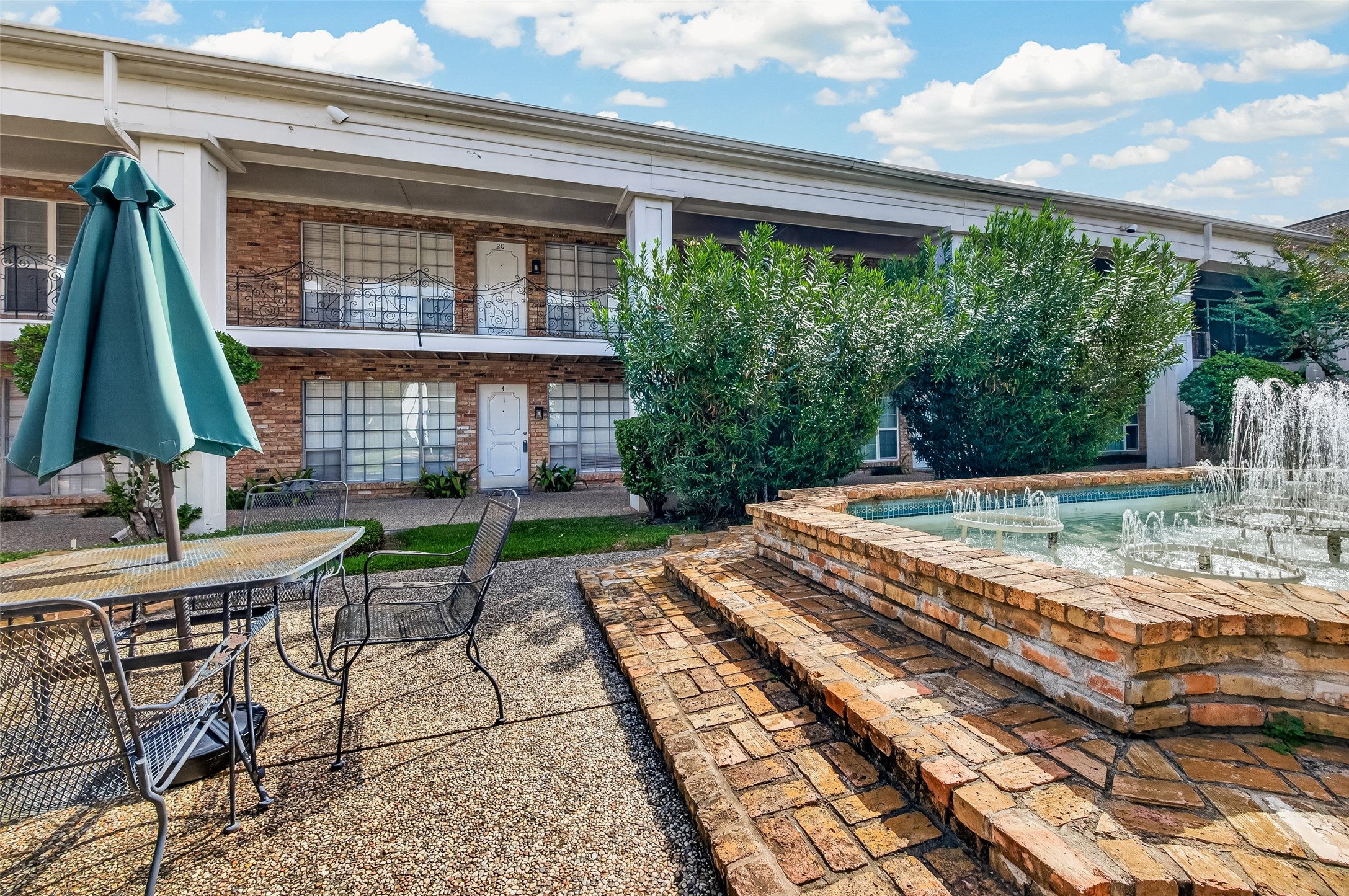 Charming courtyard with a tranquil fountain, lush greenery, and a cozy seating area perfect for relaxation.