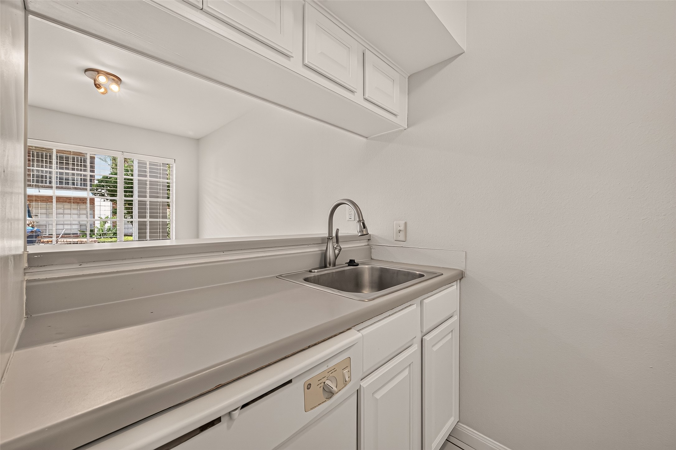 Compact kitchen area with sleek countertops, a stainless steel sink, and ample cabinetry, offering a clean and functional space.