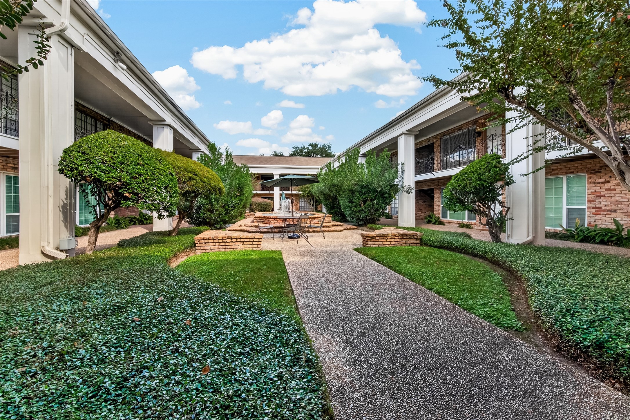 Charming courtyard setting with manicured landscaping, featuring a central seating area and elegant architectural details.