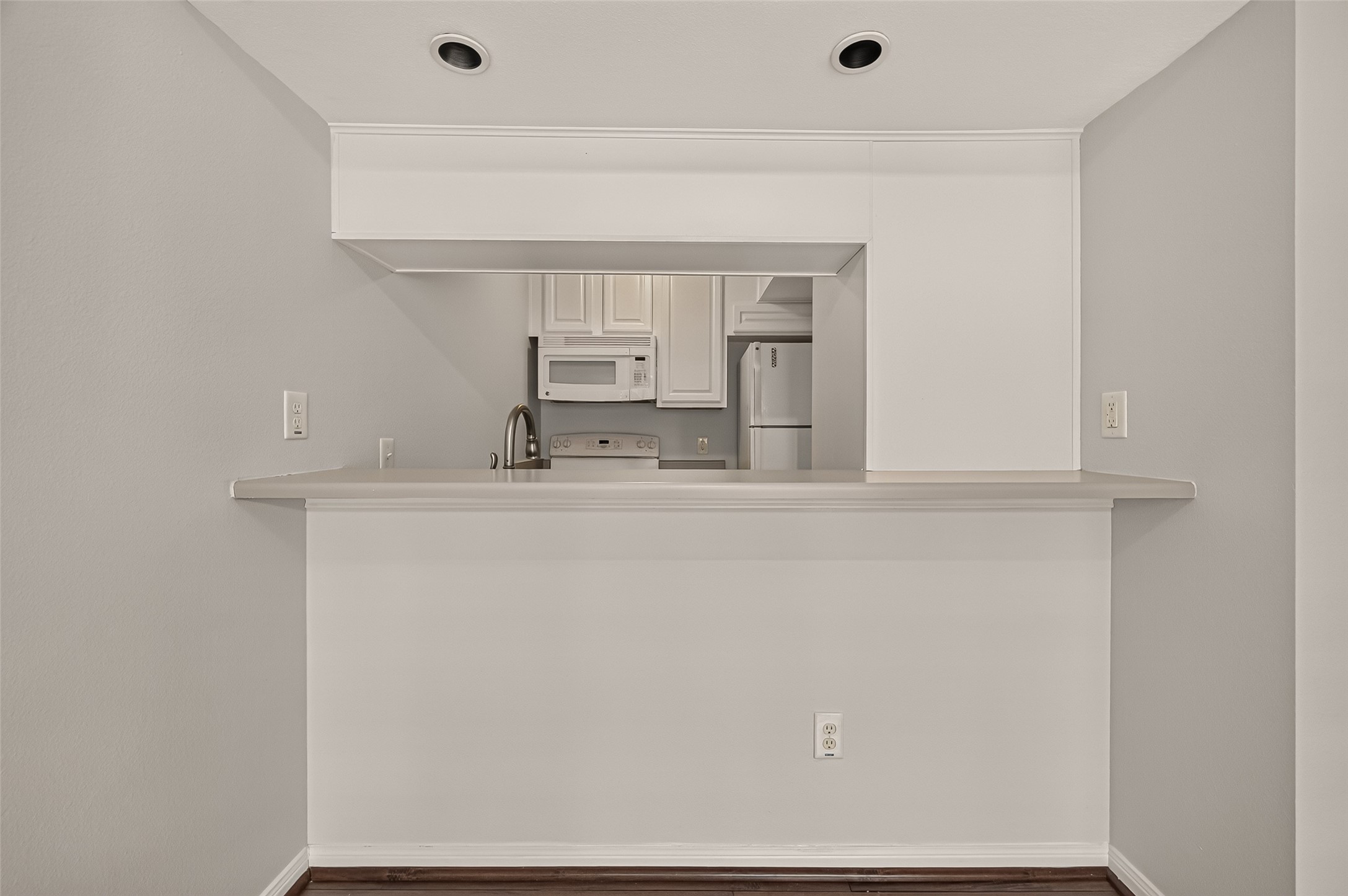 Cozy kitchen with a pass-through bar, featuring sleek white cabinetry, modern appliances, and recessed lighting for a bright, inviting space.