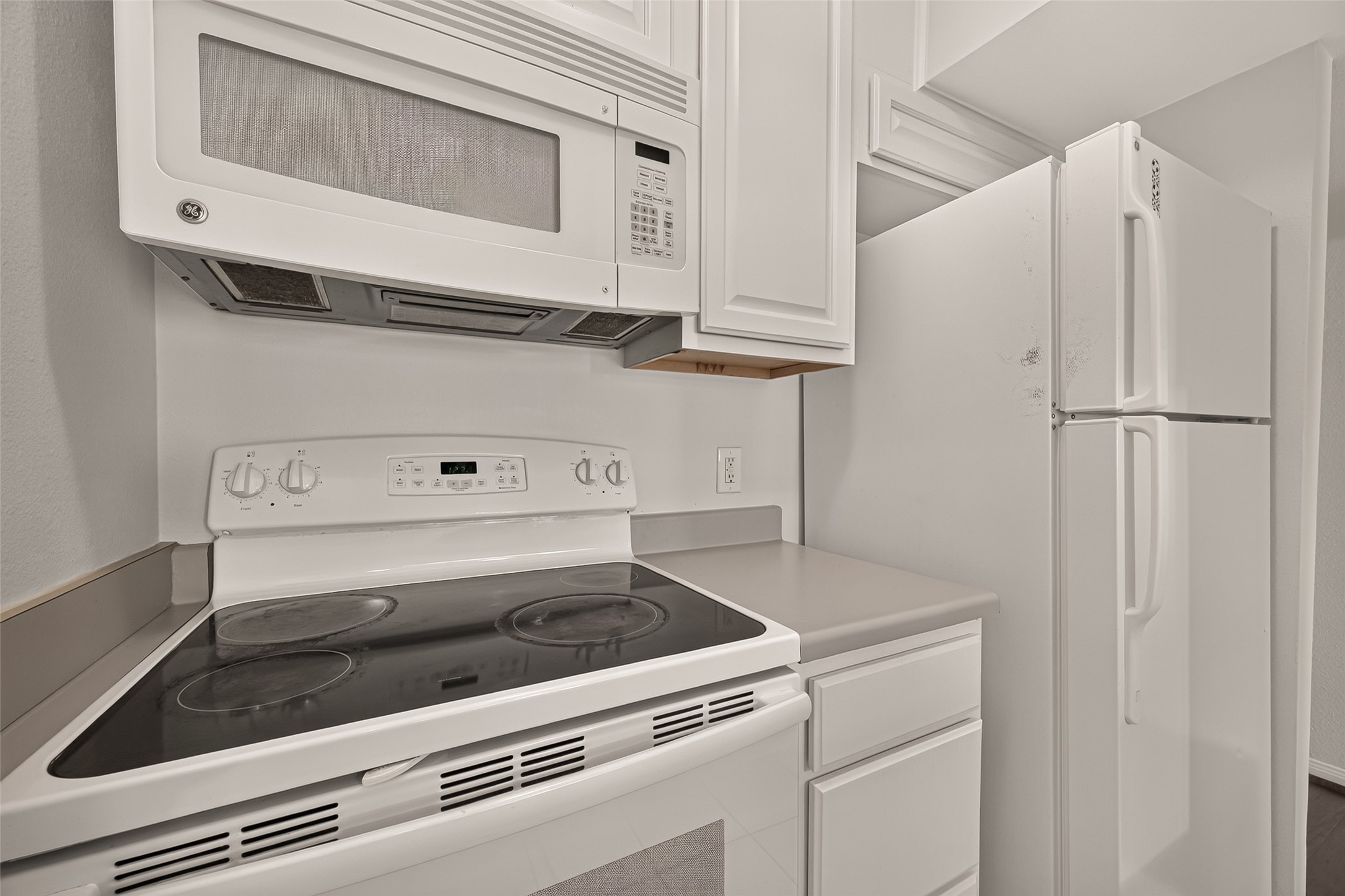 Modern kitchen equipped with sleek white appliances, including a stove, microwave, and refrigerator, complemented by ample cabinetry for storage.