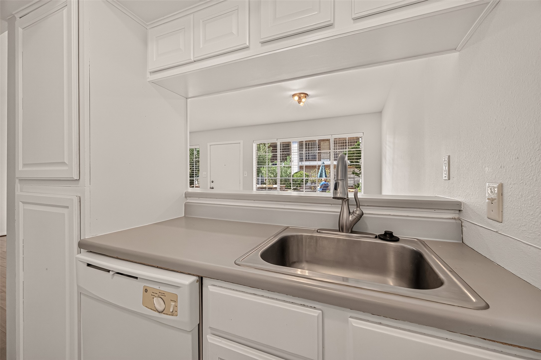 Bright kitchen with a sleek stainless steel sink and convenient pass-through window to the living area, enhancing the open-concept feel.