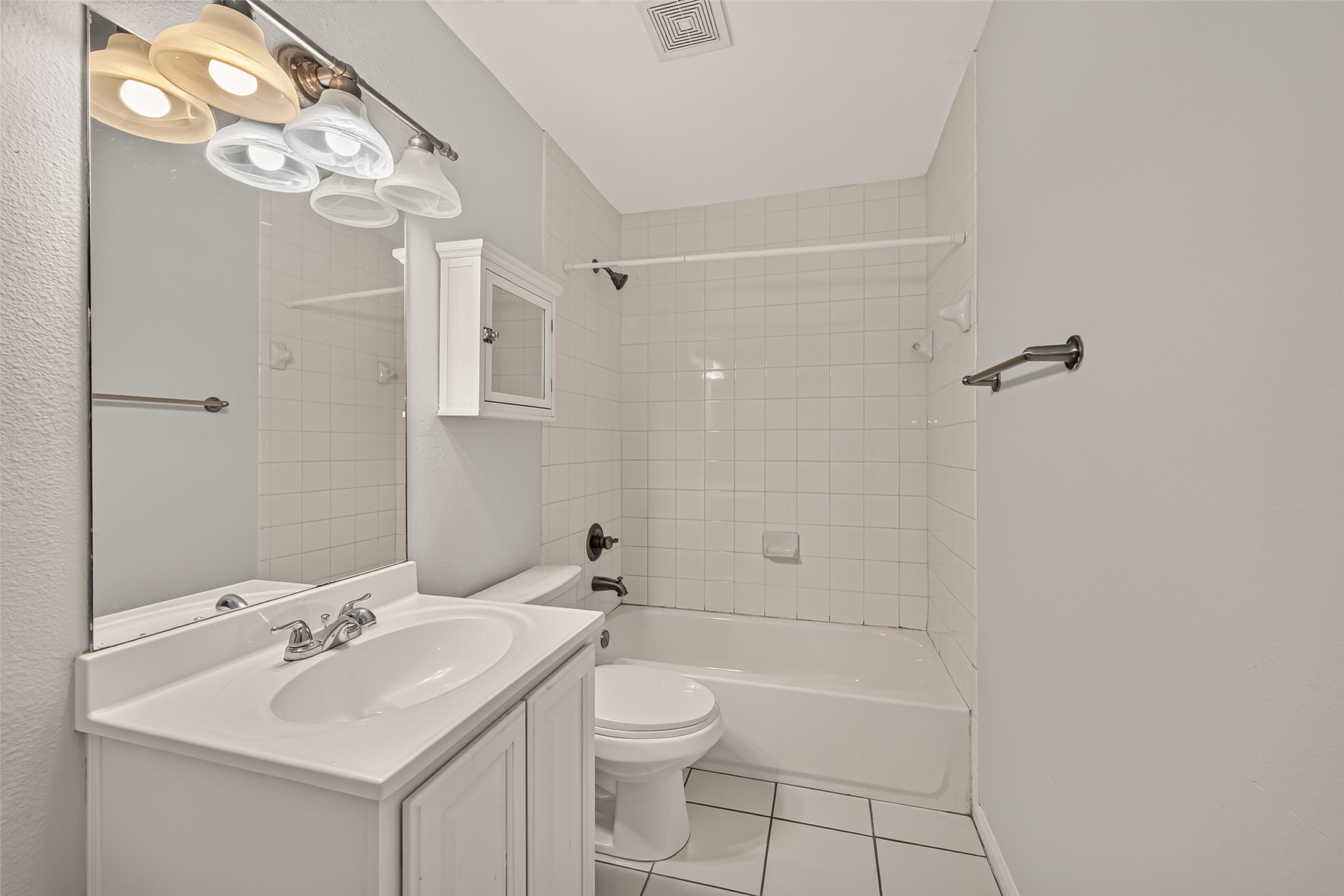 Modern bathroom with sleek white tiles, a full bathtub, and a stylish vanity, offering a clean and bright space for relaxation.