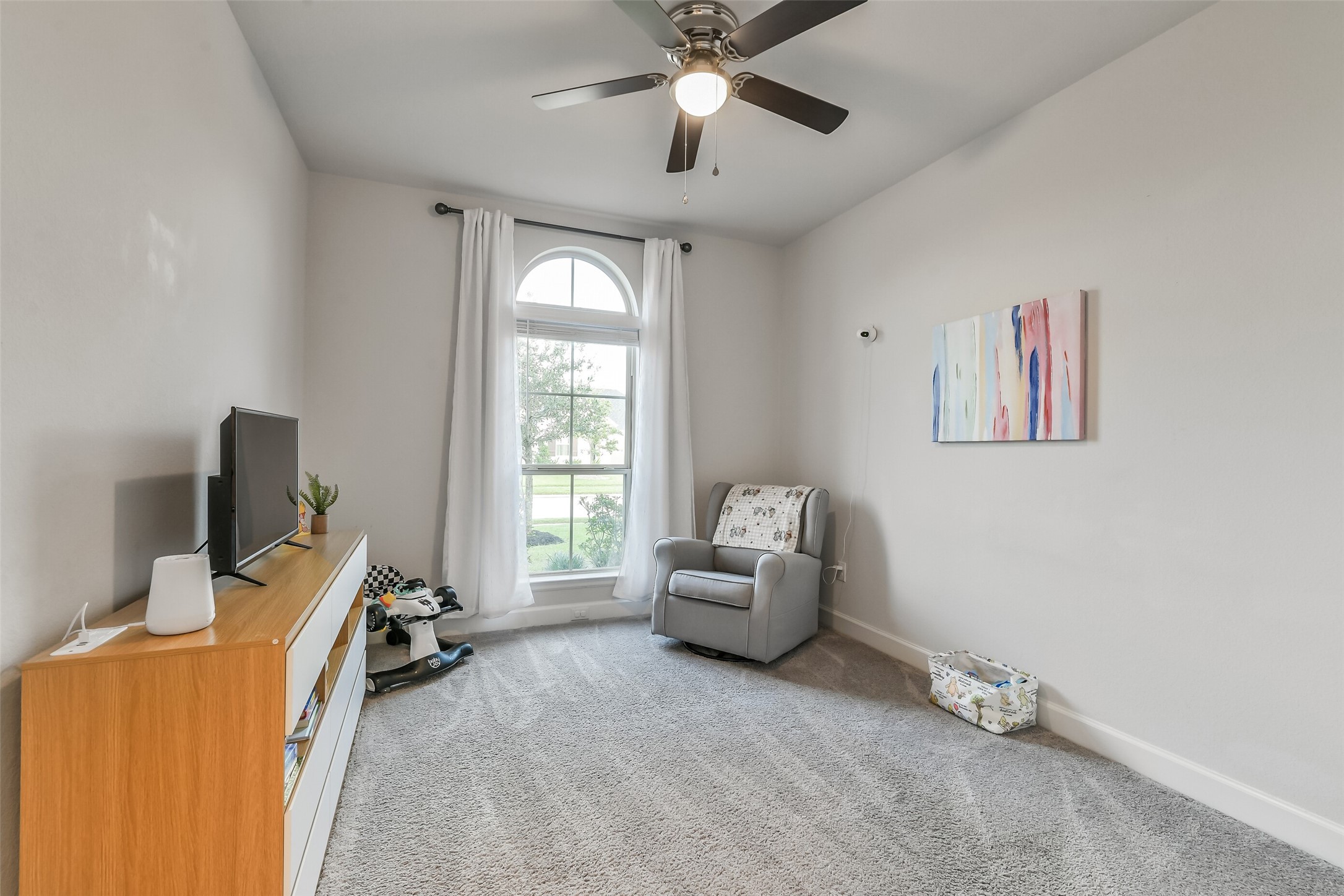 Secondary bedroom #1 features a beautiful arched window and ceiling fan.