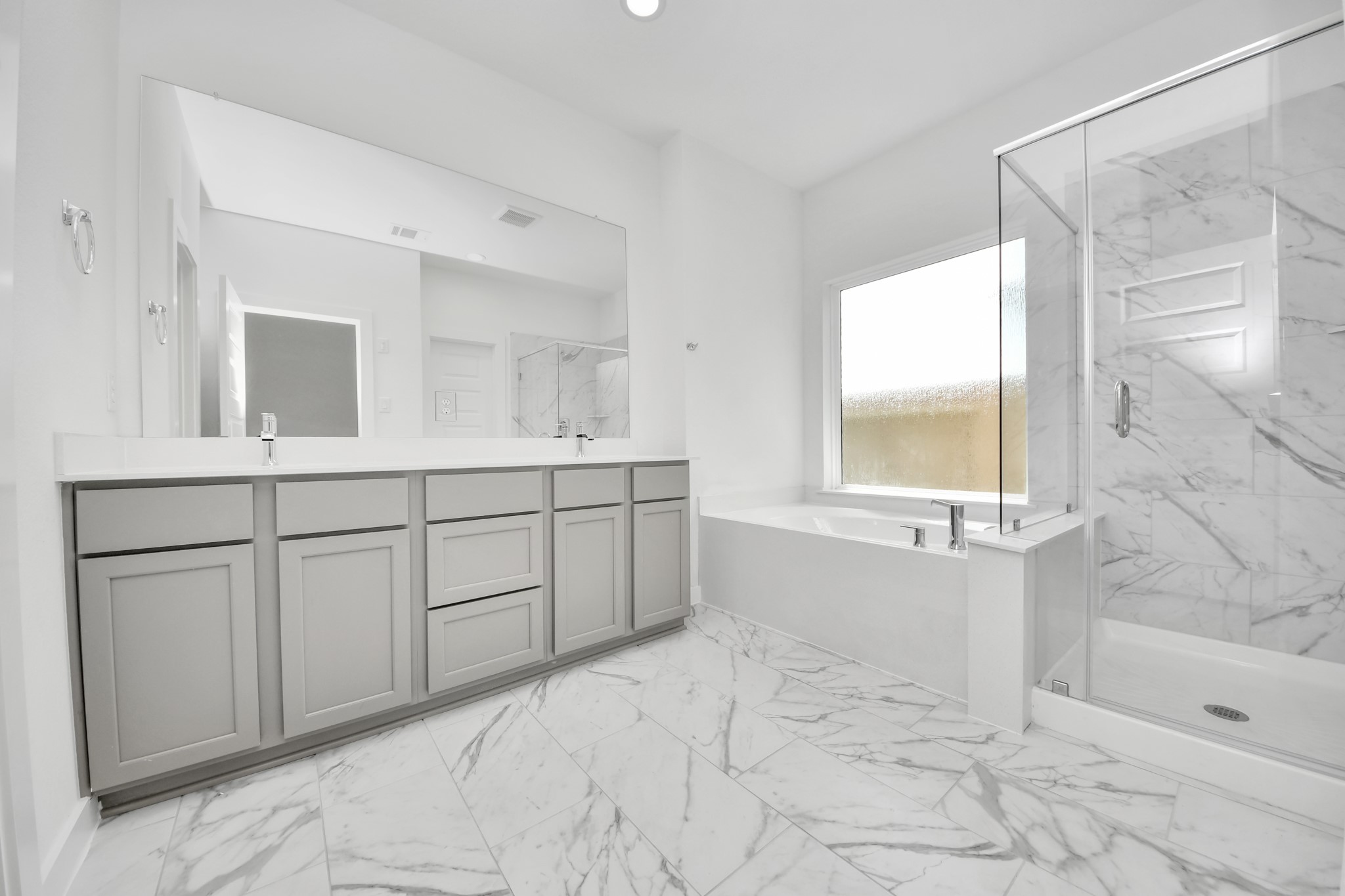 Escape to a spa-like oasis in this primary bathroom. Enjoy a walk-in shower with tile surround, a separate garden tub with custom detailing, and an elegant vanity featuring light countertops, modern hardware, and beautiful recessed lights. Experience luxury and relaxation in every detail. Sample photo of completed home with similar floor plan. Actual colors and selections may vary.