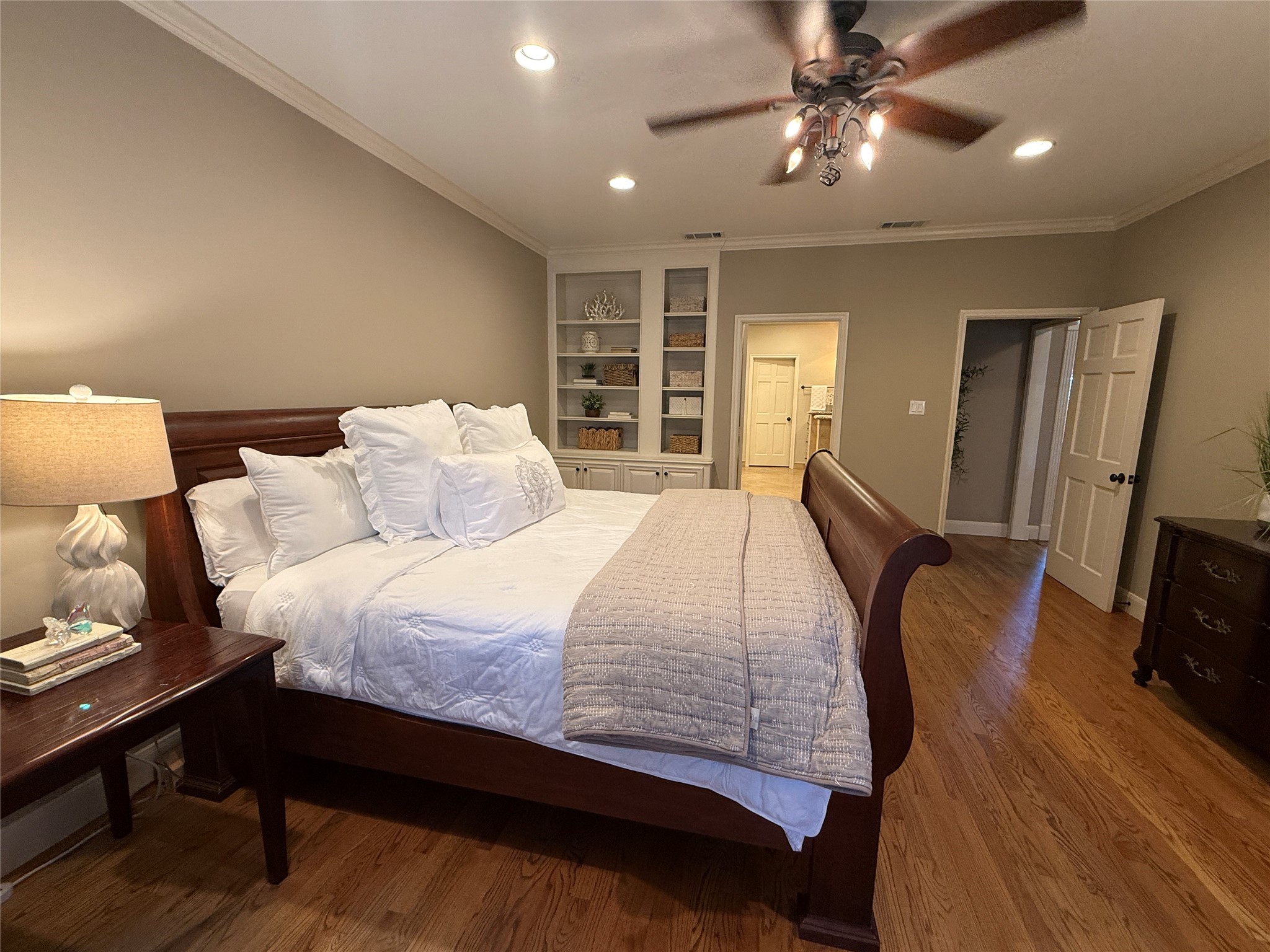 Primary bedroom with hard wood floors and built in shelves.