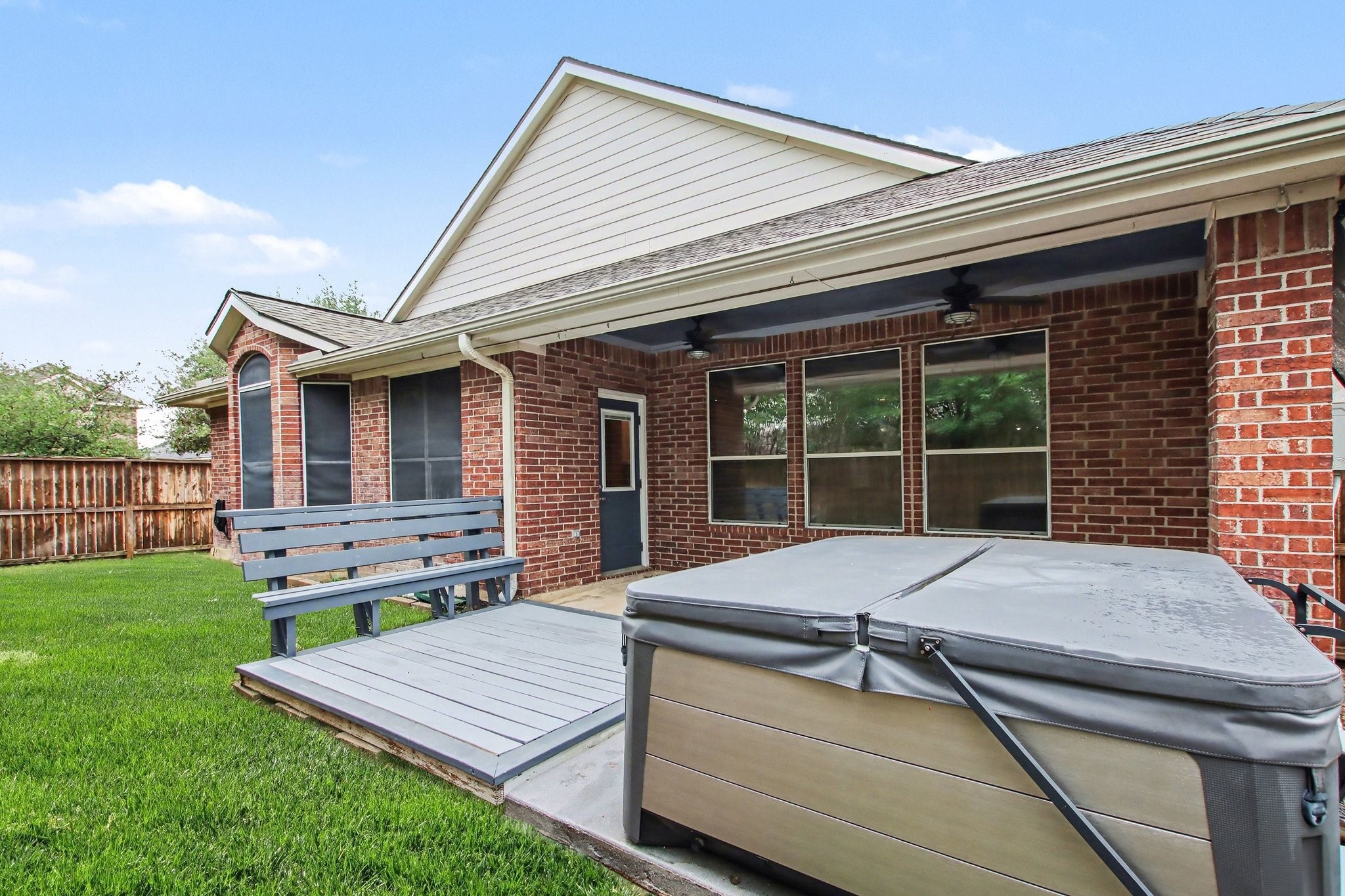 Step outside to the backyard with a massive covered patio, dual fans, an extended deck with bench seating, and a hot tub.