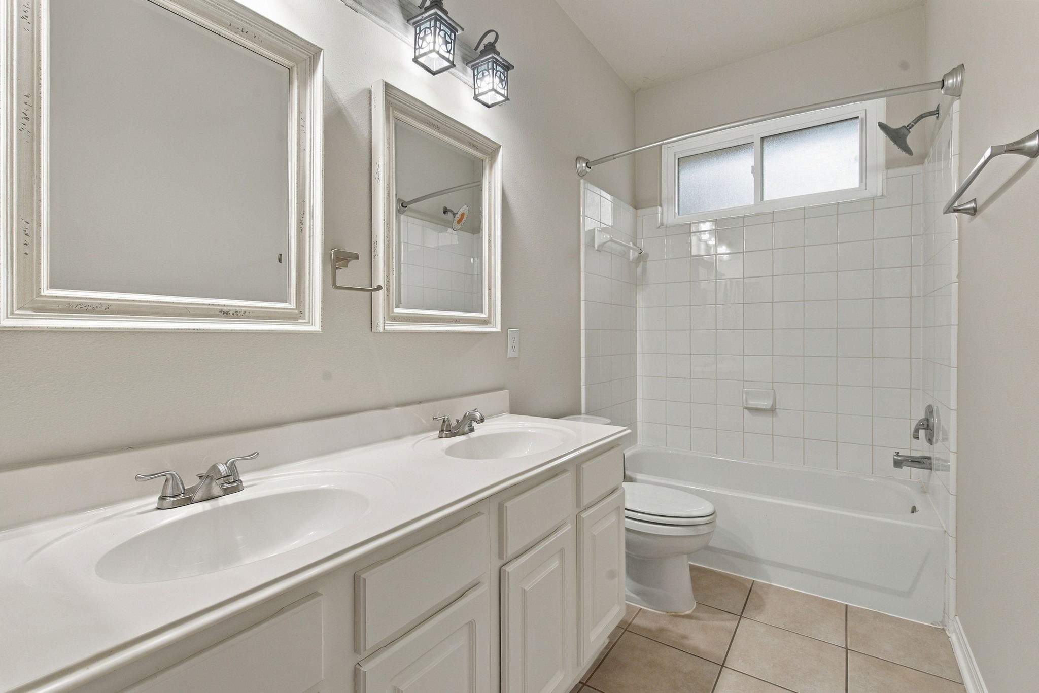 View of the downstairs full bath off the secondary bedrooms with dual sinks and a combination tub and shower.