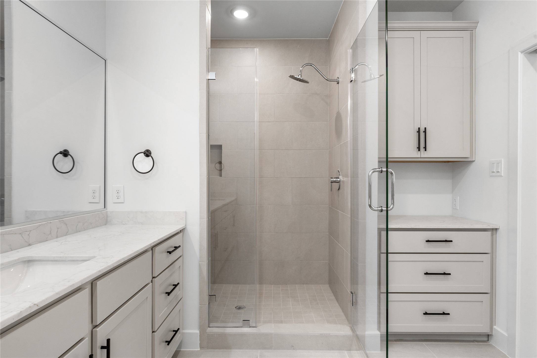 Custom primary shower & vanity  large-format tile surround, rain showerhead, grey shaker vanity with quartz counter, and built-in linen storage tower.