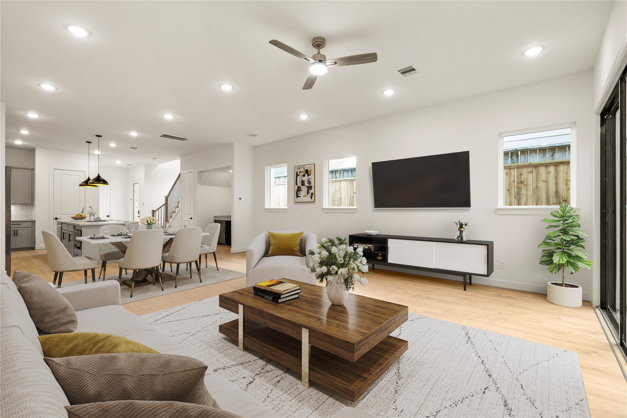 Spacious entertainer's lounge  low-profile coffee table, wall-mounted media center, natural light from surrounding windows, and effortless connection to the dining and kitchen quarters.