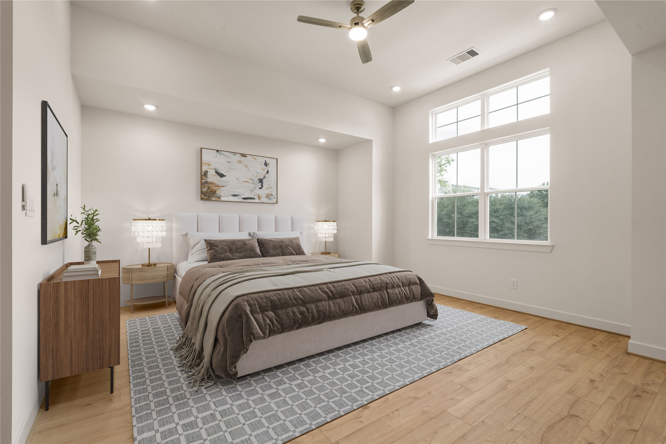 Primary bedroom retreat  tufted upholstered bed, high architectural ceiling with transom windows streaming morning light, sleek wooden dresser, and modern ceiling fan.