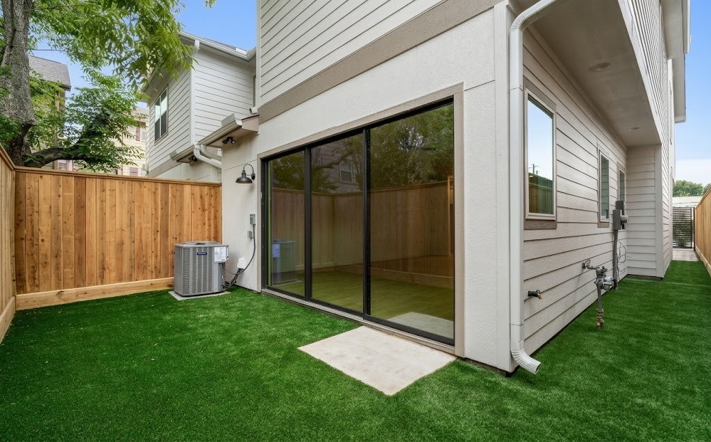 Private backyard low-maintenance artificial turf, privacy fencing, direct glass sliding door access, and covered exterior entry.
