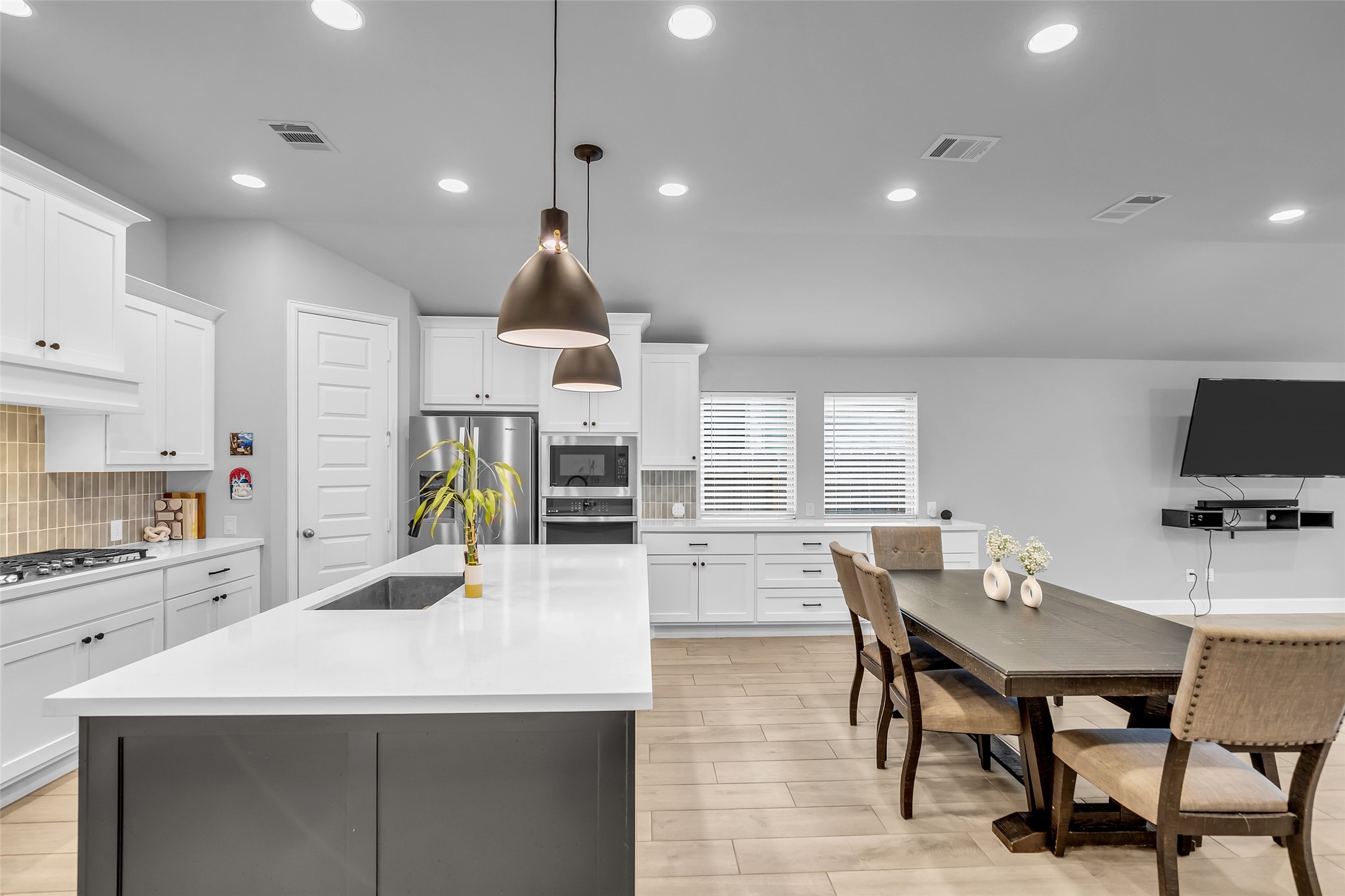 Discover Your Modern Kitchen Featuring Sleek, White Cabinetry, A Spacious Island w/ Sink, & In-Ceiling Lighting. The Open Layout Seamlessly Connects To A Cozy, Dining Area w/ Long Buffet, Perfect For Entertaining!Gas