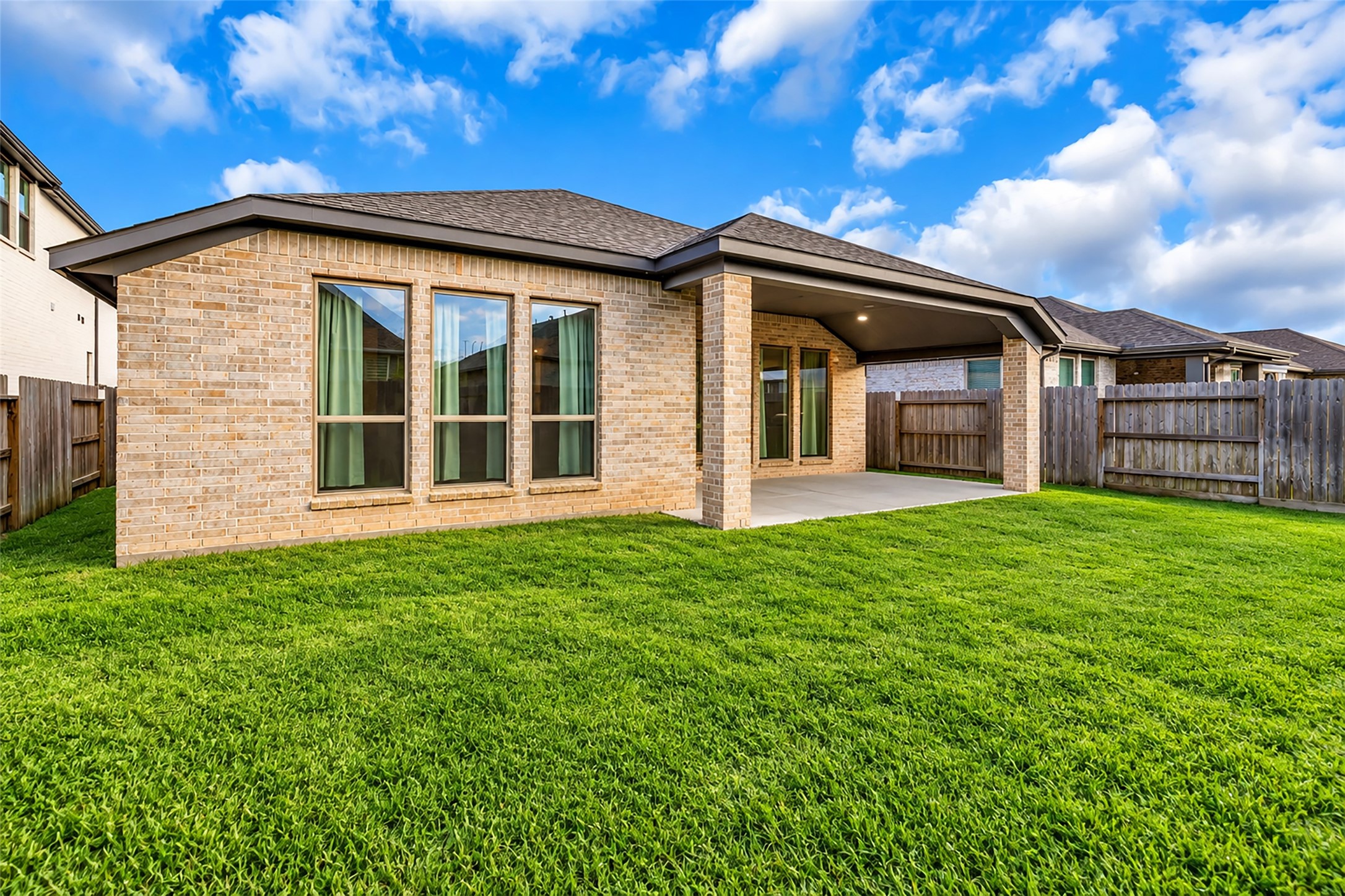 Charming backyard with a spacious covered patio, perfect for outdoor entertaining, surrounded by a well-maintained lawn and privacy fence.