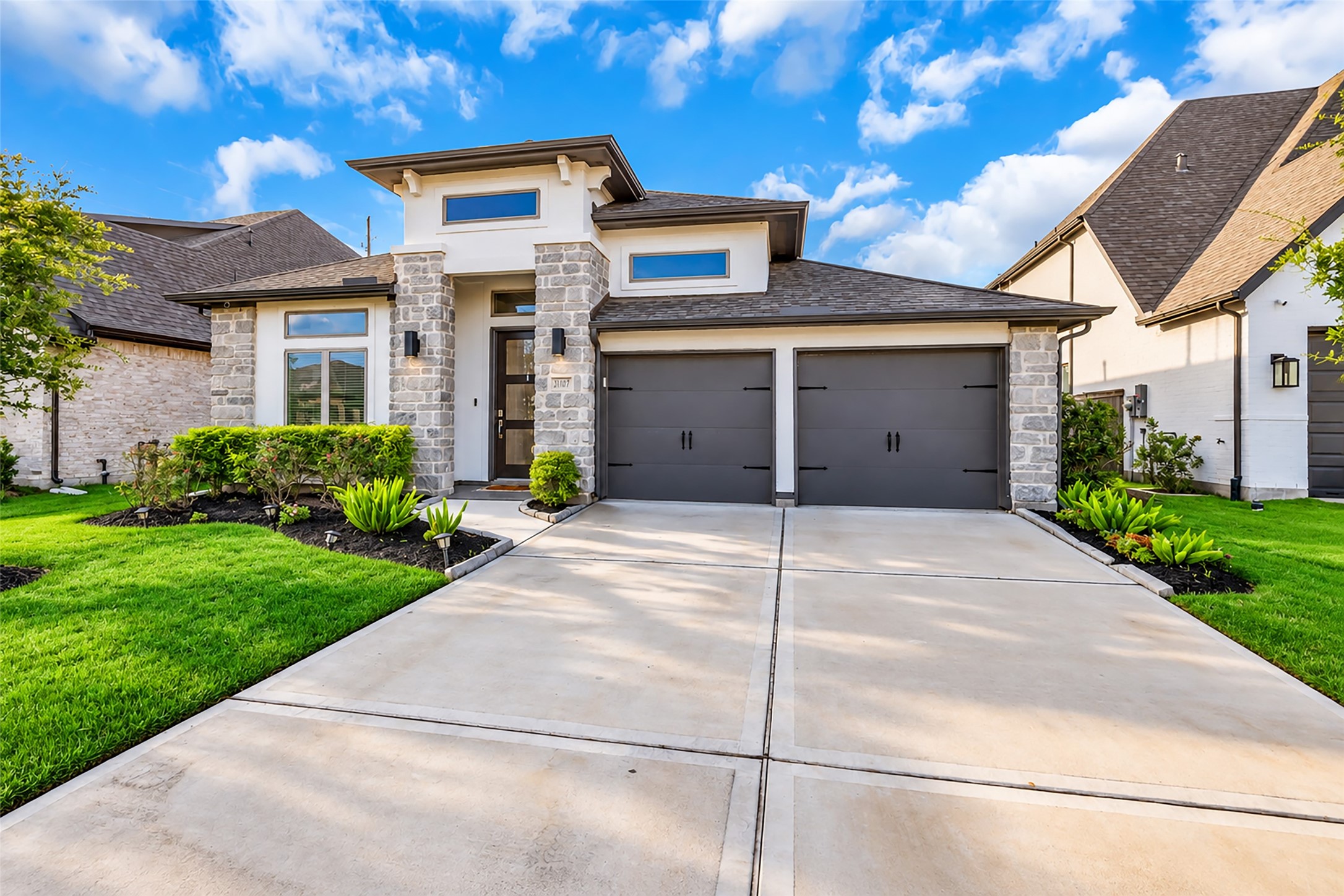 Your Stunning, Modern Home w/ Dual Garage, Elegant Stone Accents, & Lush Landscaping On A Spacious, Double-Wide Driveway.