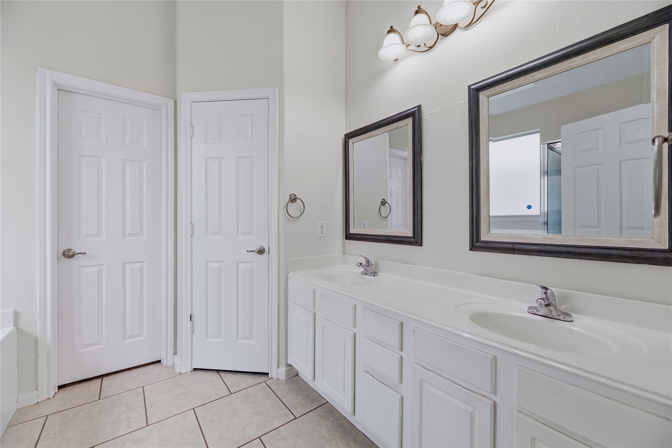 Two sinks and separate mirrors make it easier to share the primary vanity, while drawers and cabinets offer space for everyday bath essentials.