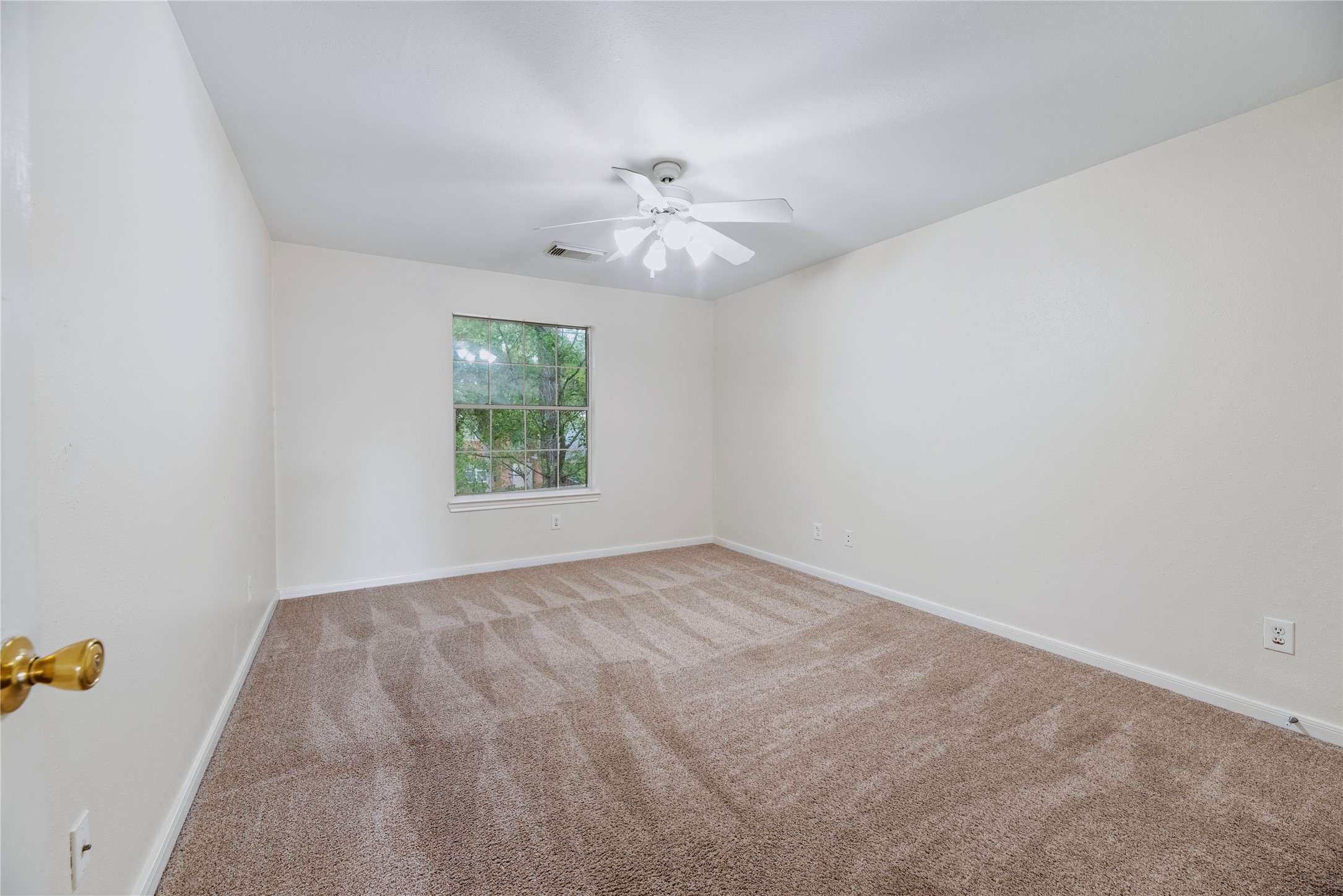 Another secondary bedroom offers a window, ceiling fan and uncluttered floor space, providing flexibility for sleeping or a separate workspace.